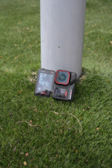 Action camera resting on grass next to pole