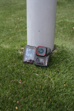 Action camera resting on grass next to pole