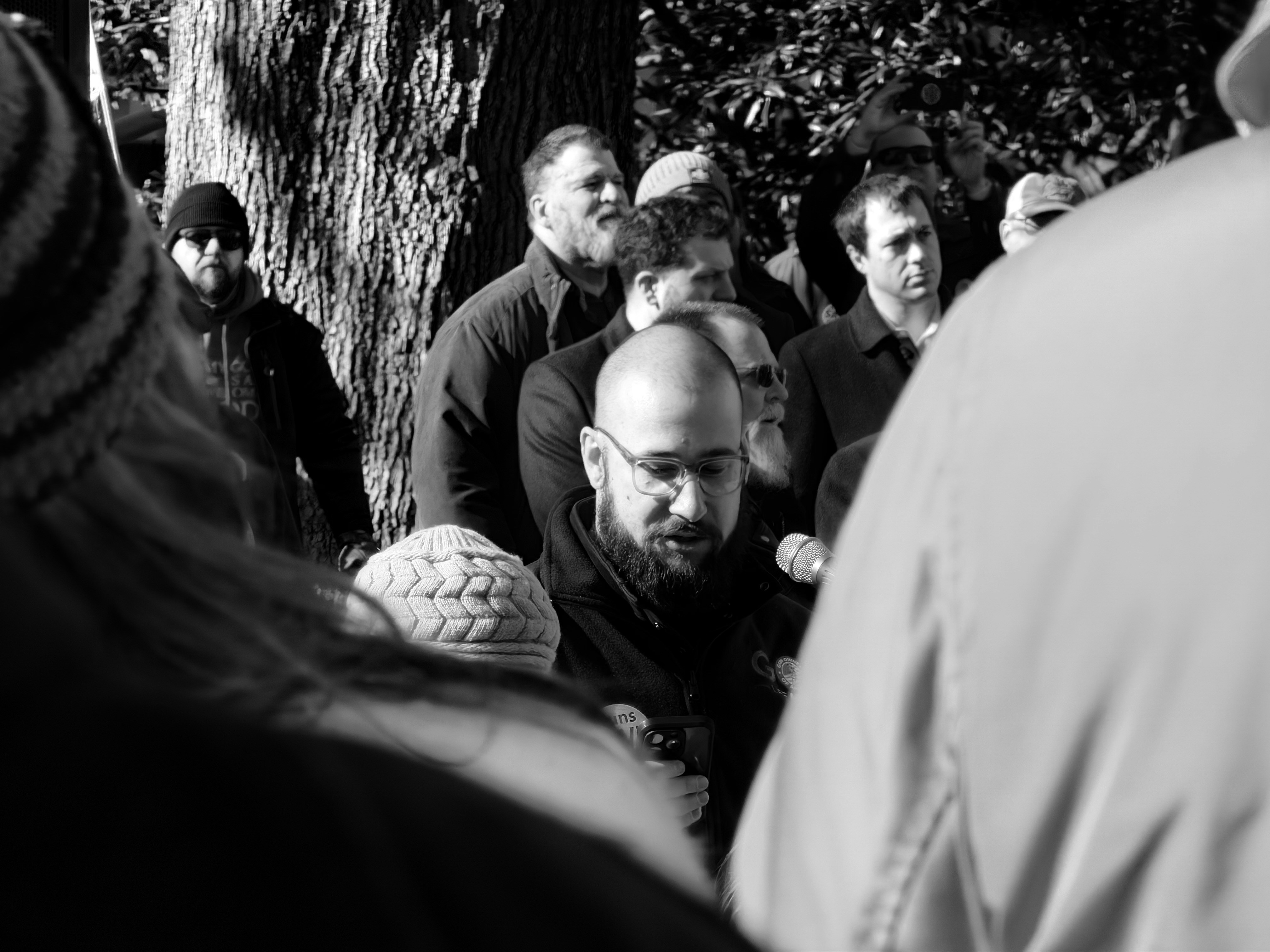 A group of men gathered outdoors in black and white.