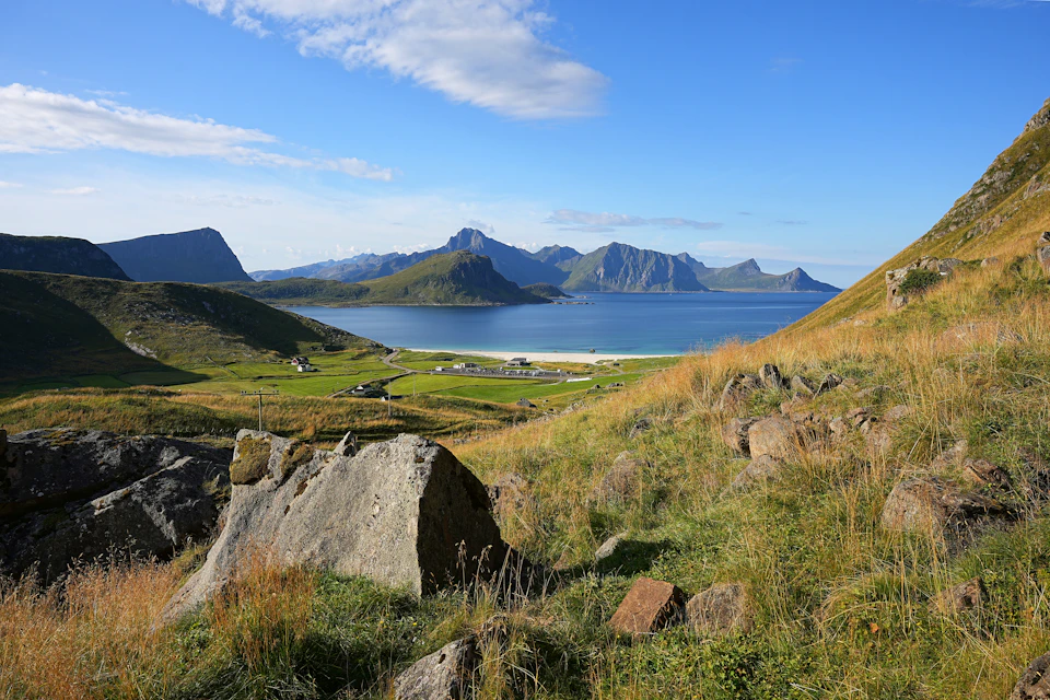 Serene landscape features large rock formation overlooking lush valley surrounded by majestic mountains