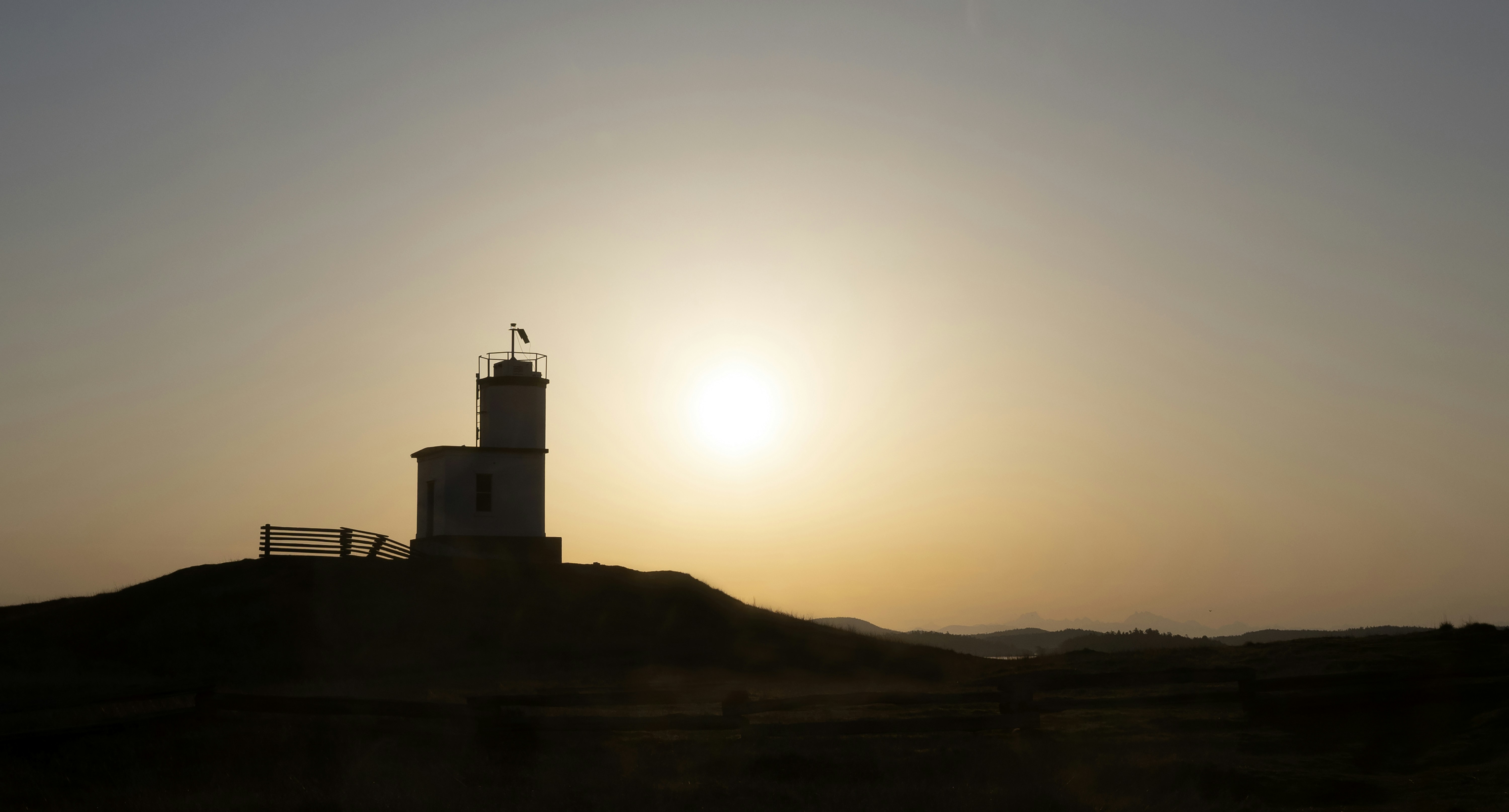 Faro recortado contra un atardecer brillante