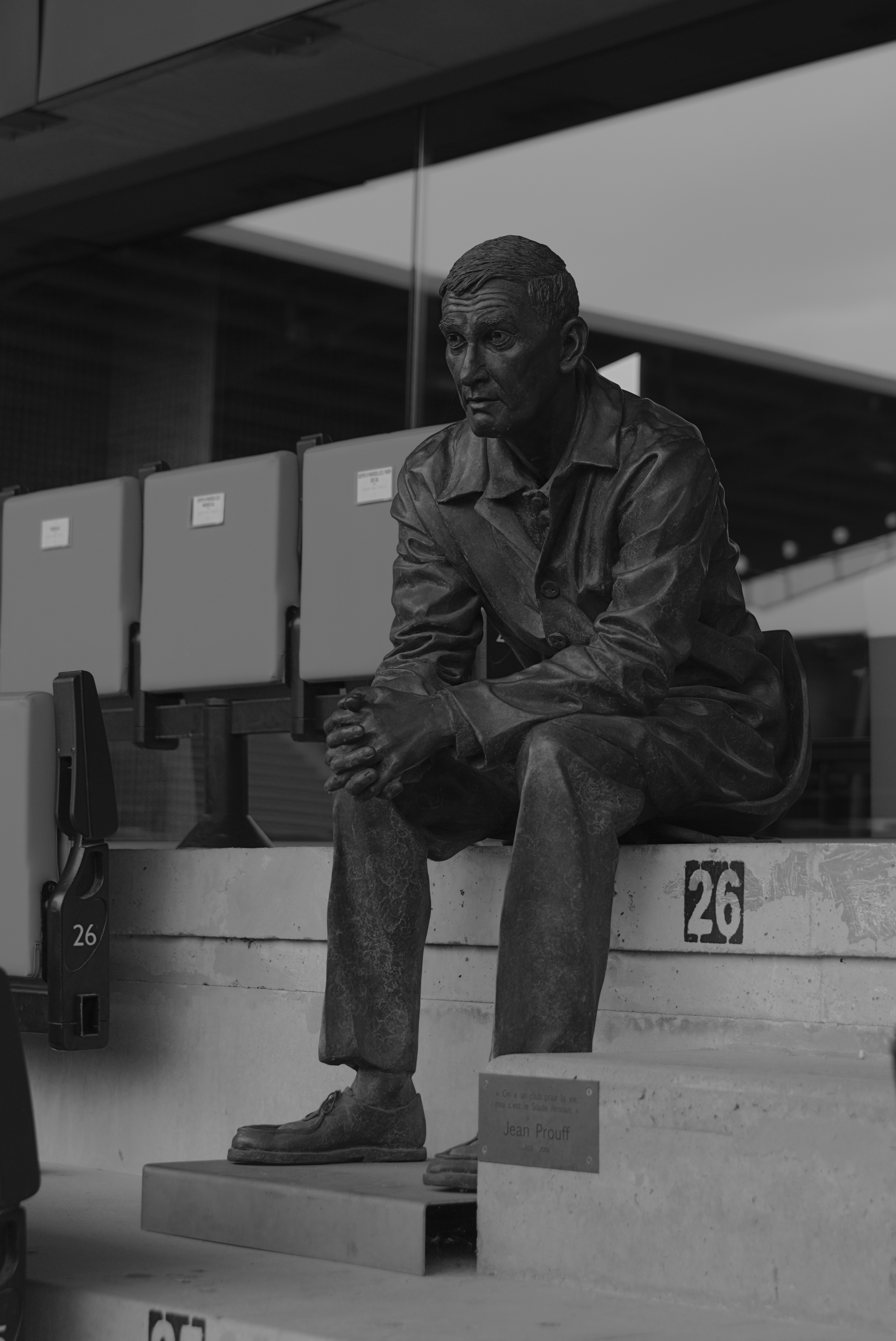 Bronze statue of a man sitting on stadium seats.