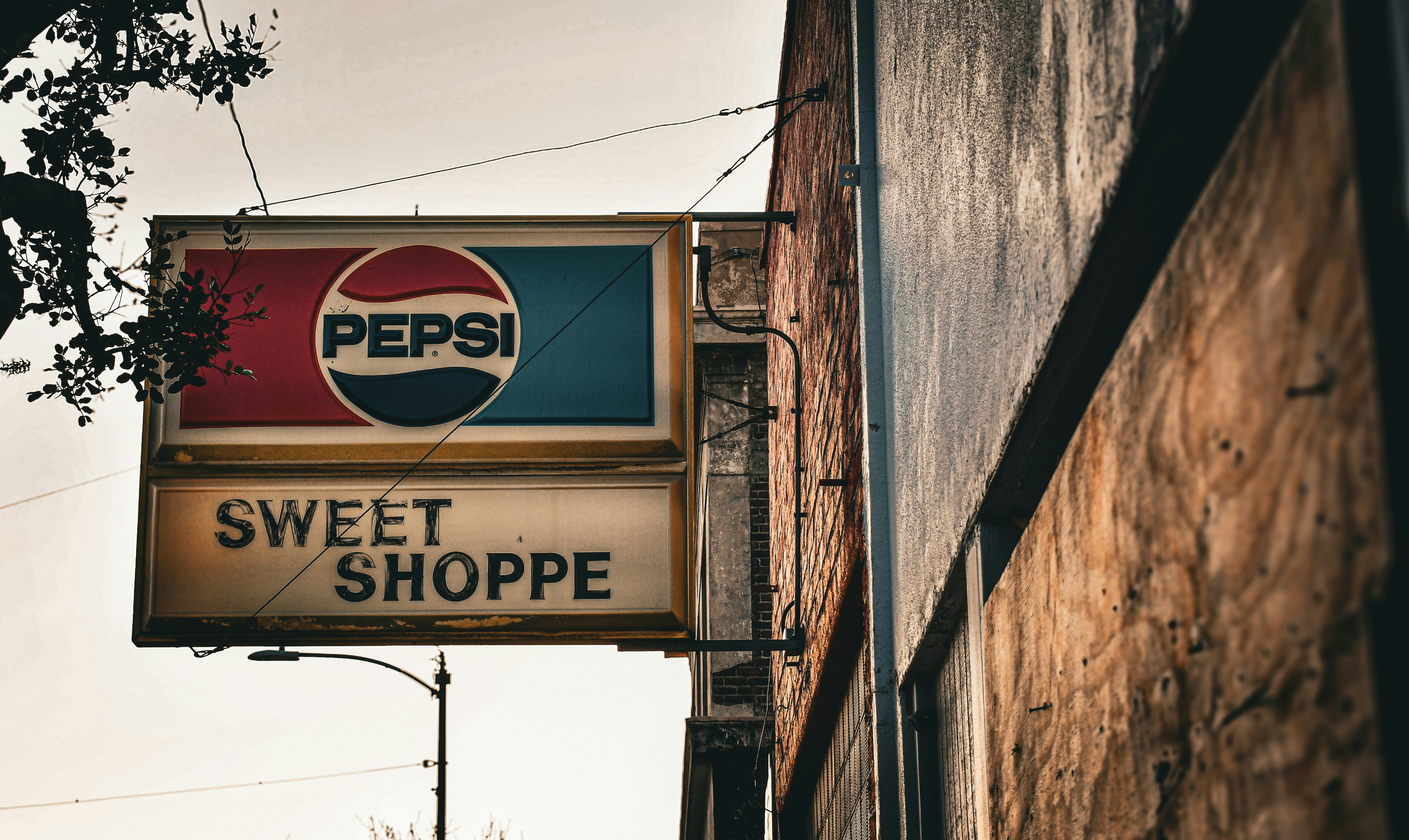 Vecchio cartello Pepsi sopra una vetrina di un negozio di dolciumi.