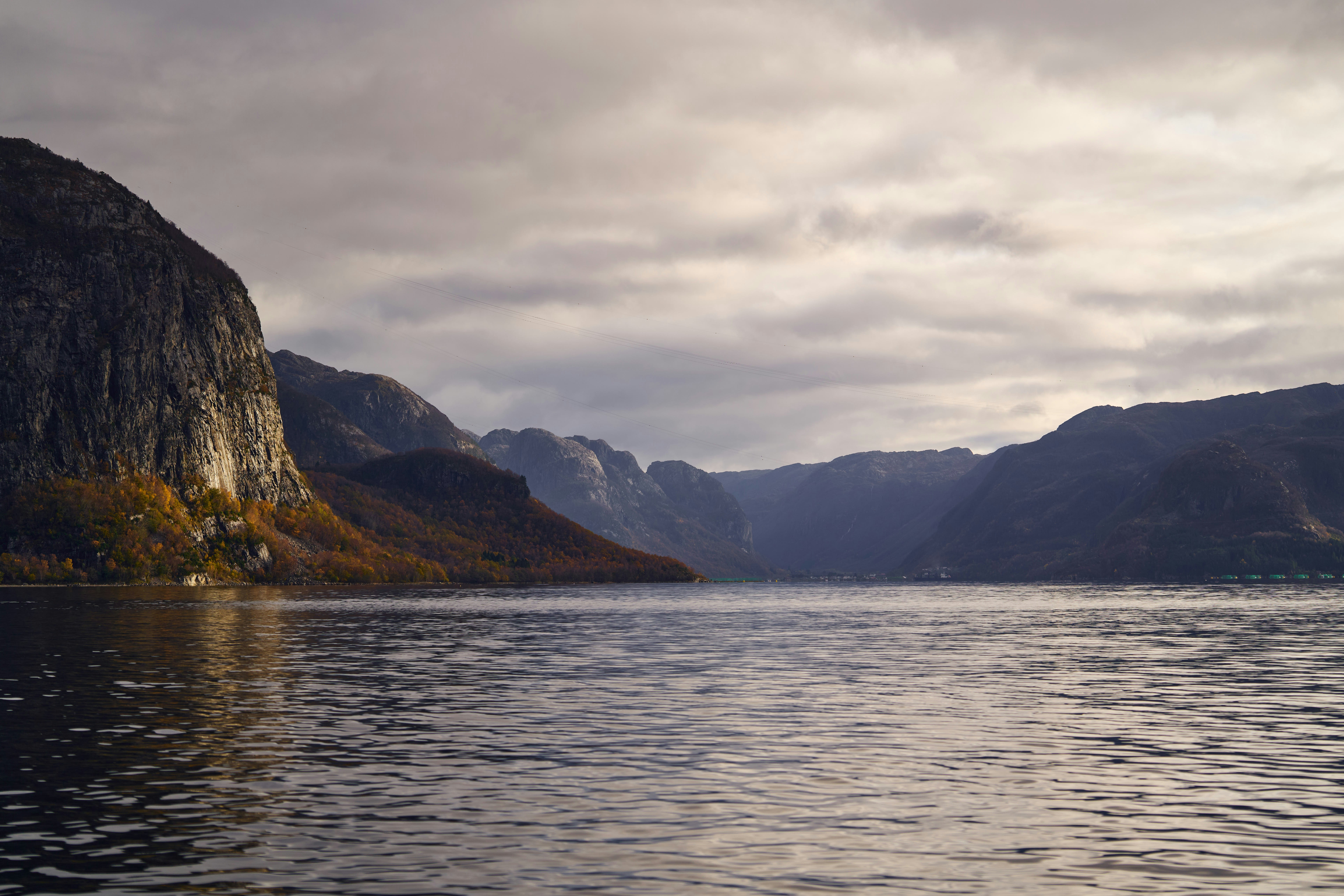 Calm lake surrounded by dramatic, cloudy mountains.