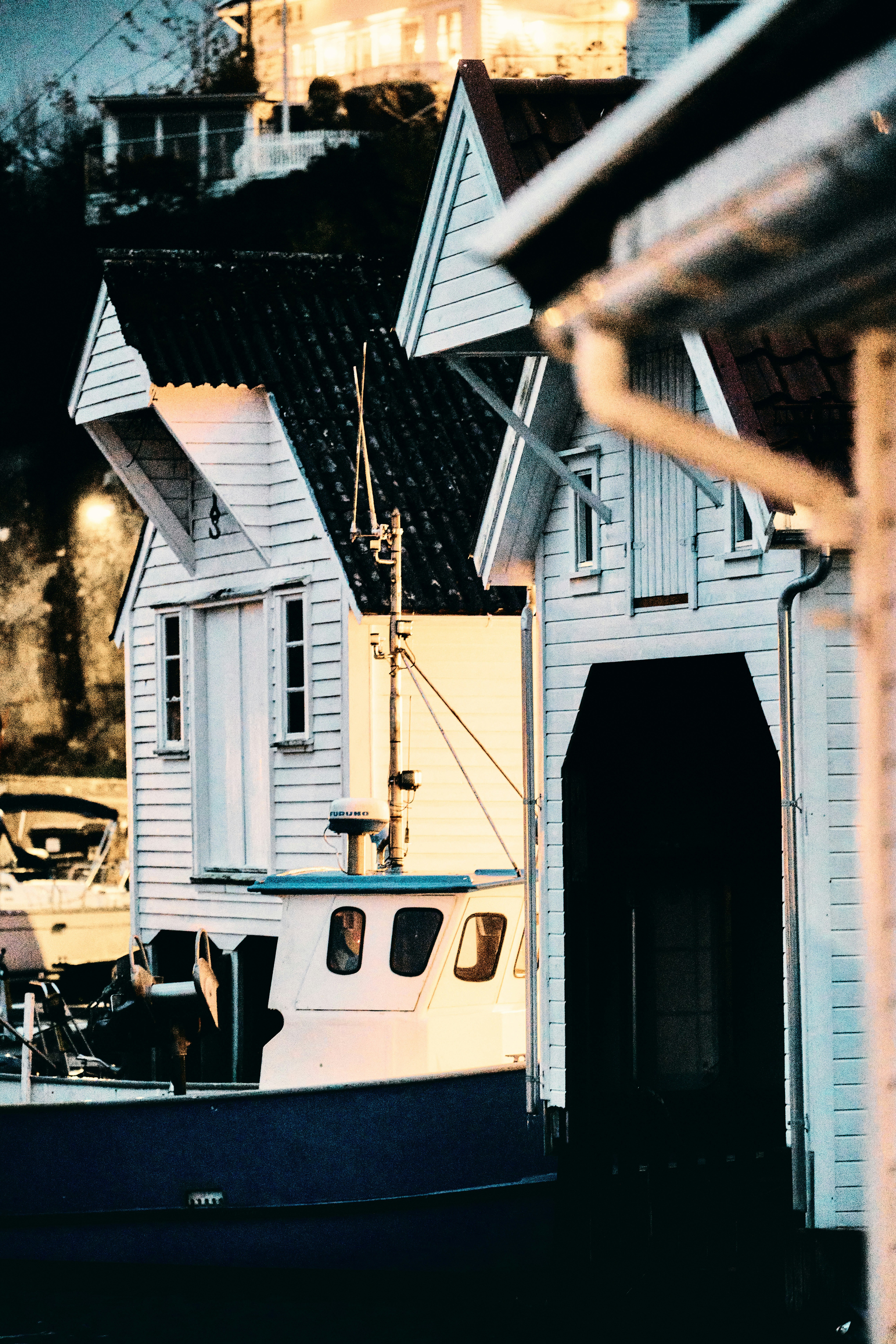 A small boat docked next to white wooden buildings.