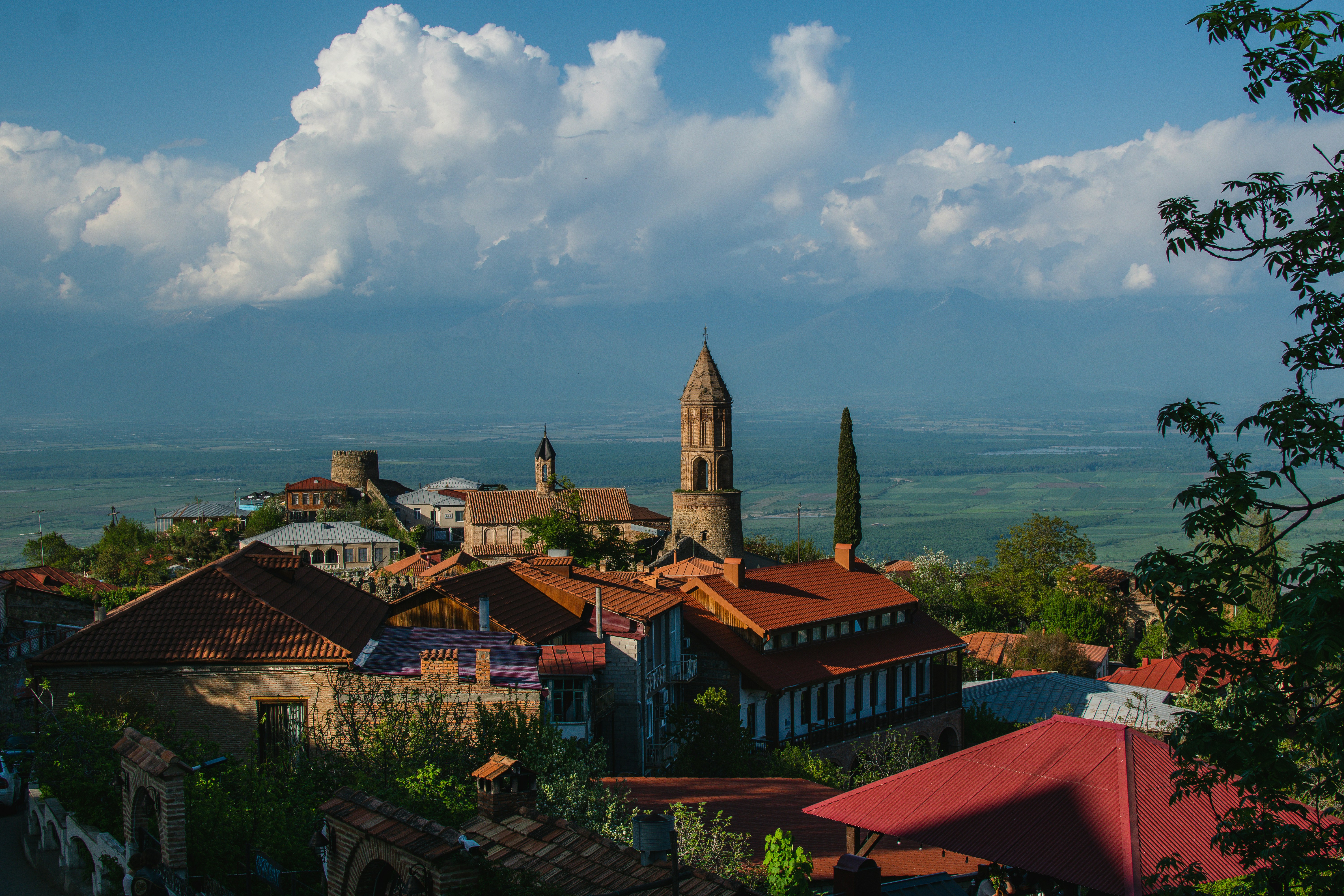 Cidade histórica com telhados de terracota e uma torre alta.