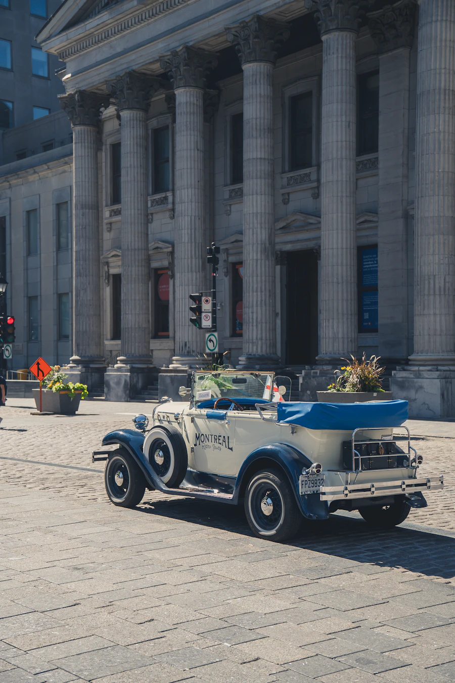 Old Montreal cobblestone street lined with grey stone heritage buildings, warm evening light, and a vintage car parked at the kerb