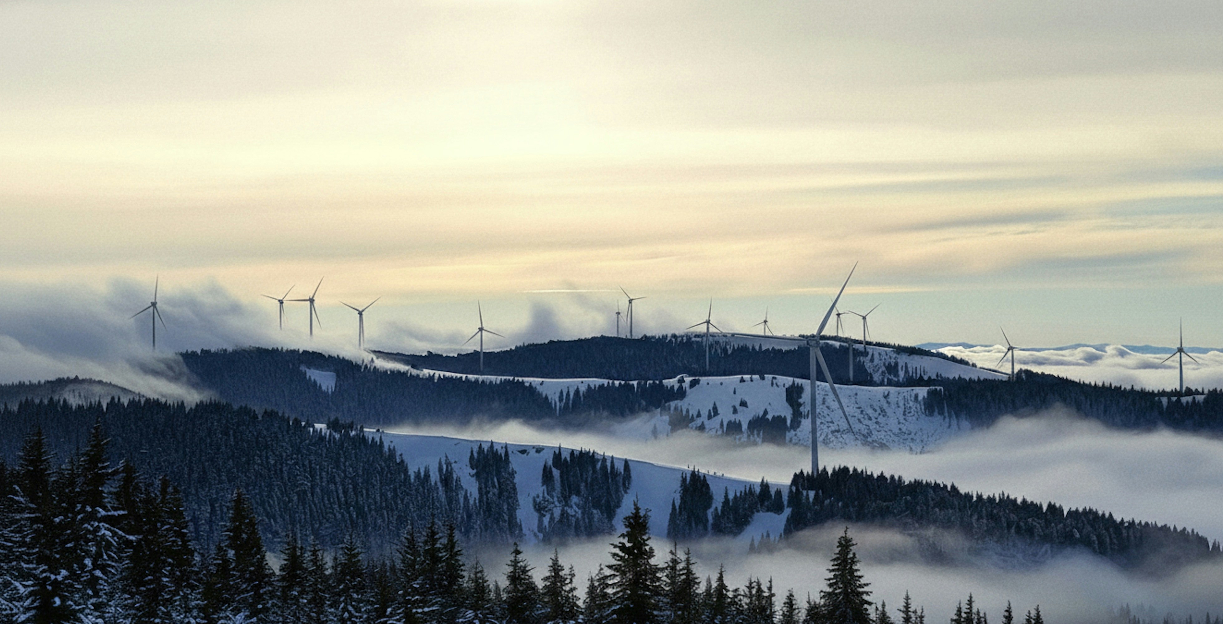 Wind turbines on misty, snow-covered mountains