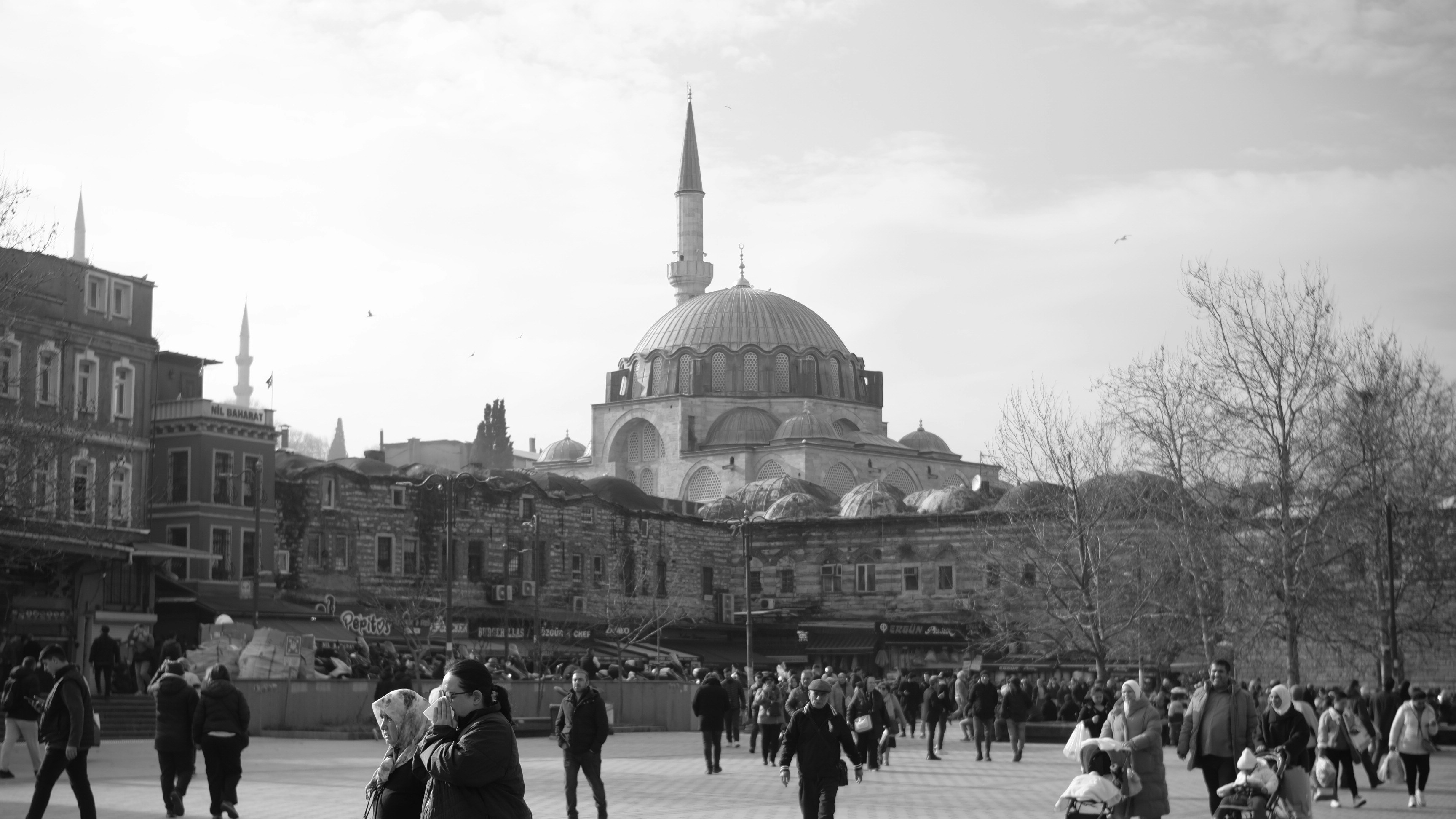 People in a square with a mosque in the background