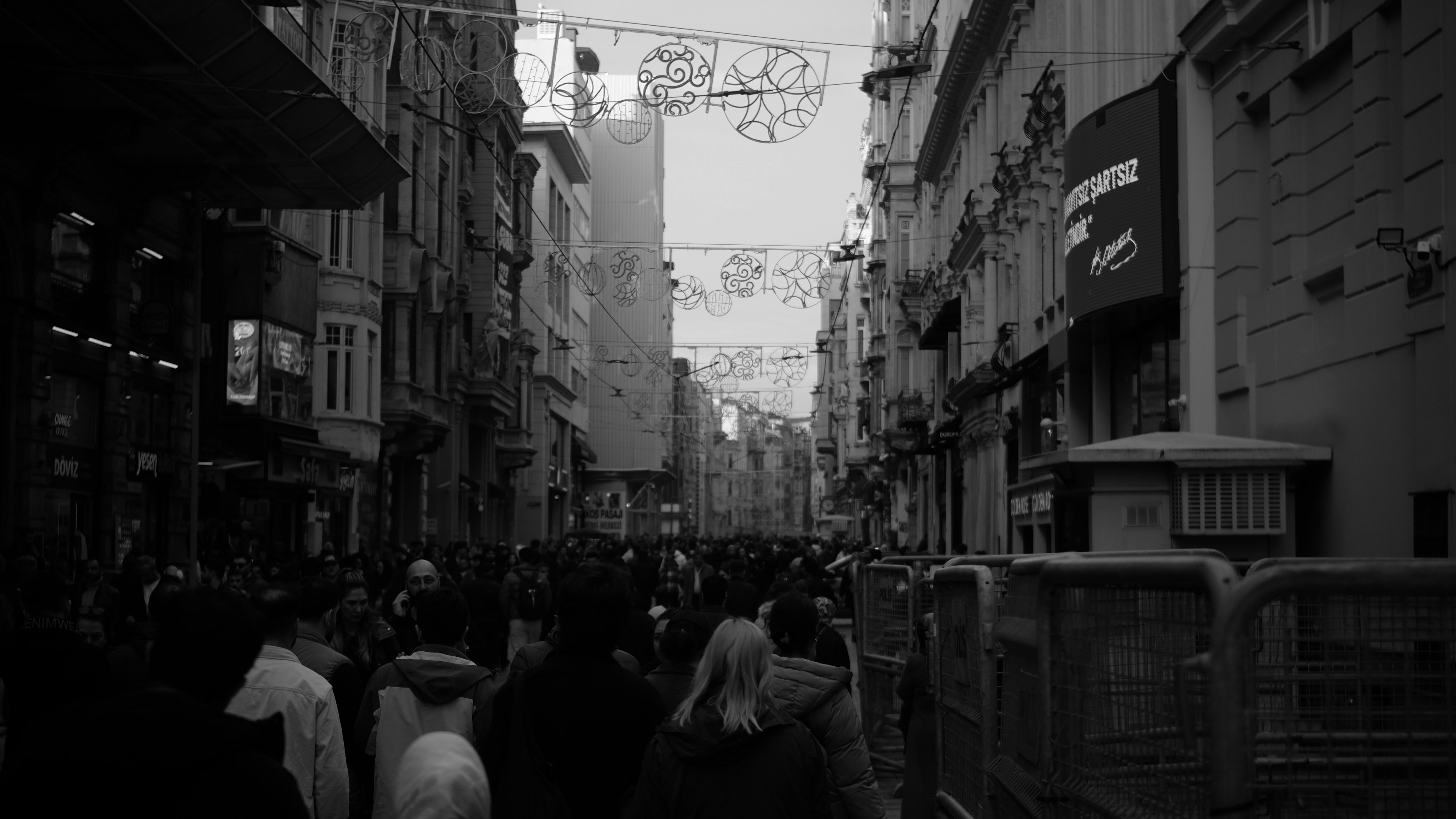 A crowded street scene with buildings and overhead decorations.