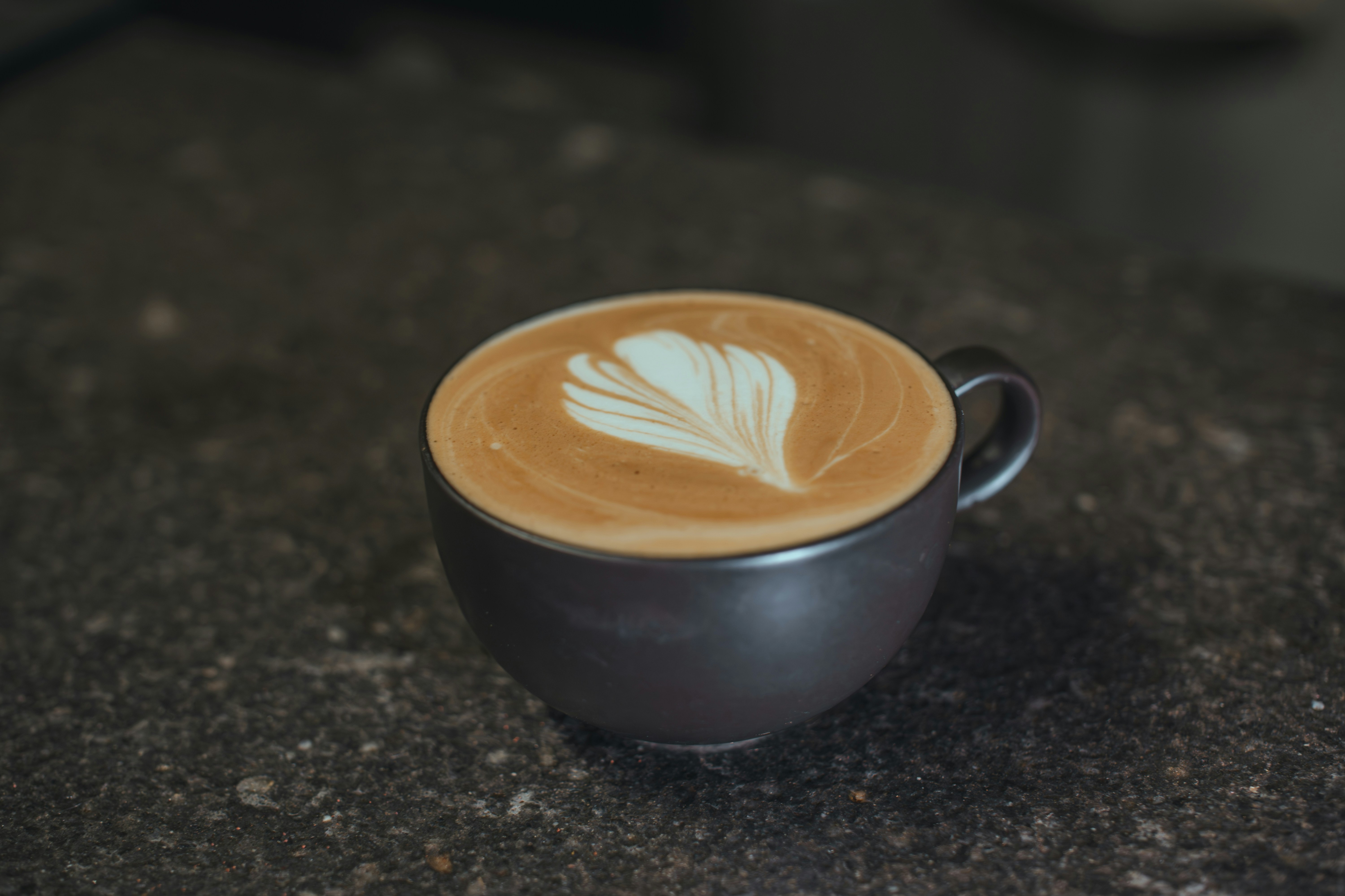 Uma caneca escura cheia de café latte art