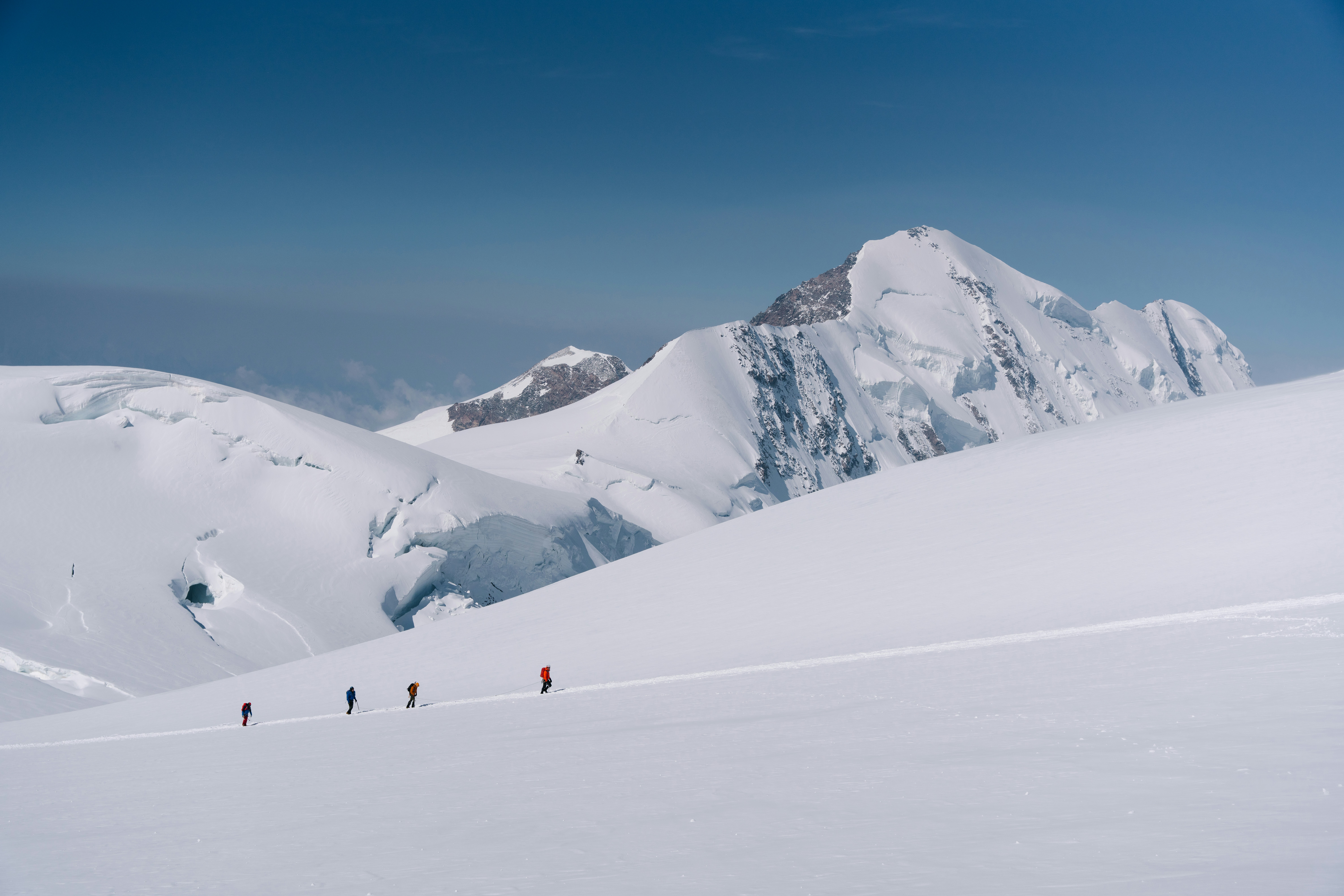Gli escursionisti attraversano un vasto paesaggio montuoso coperto di neve.