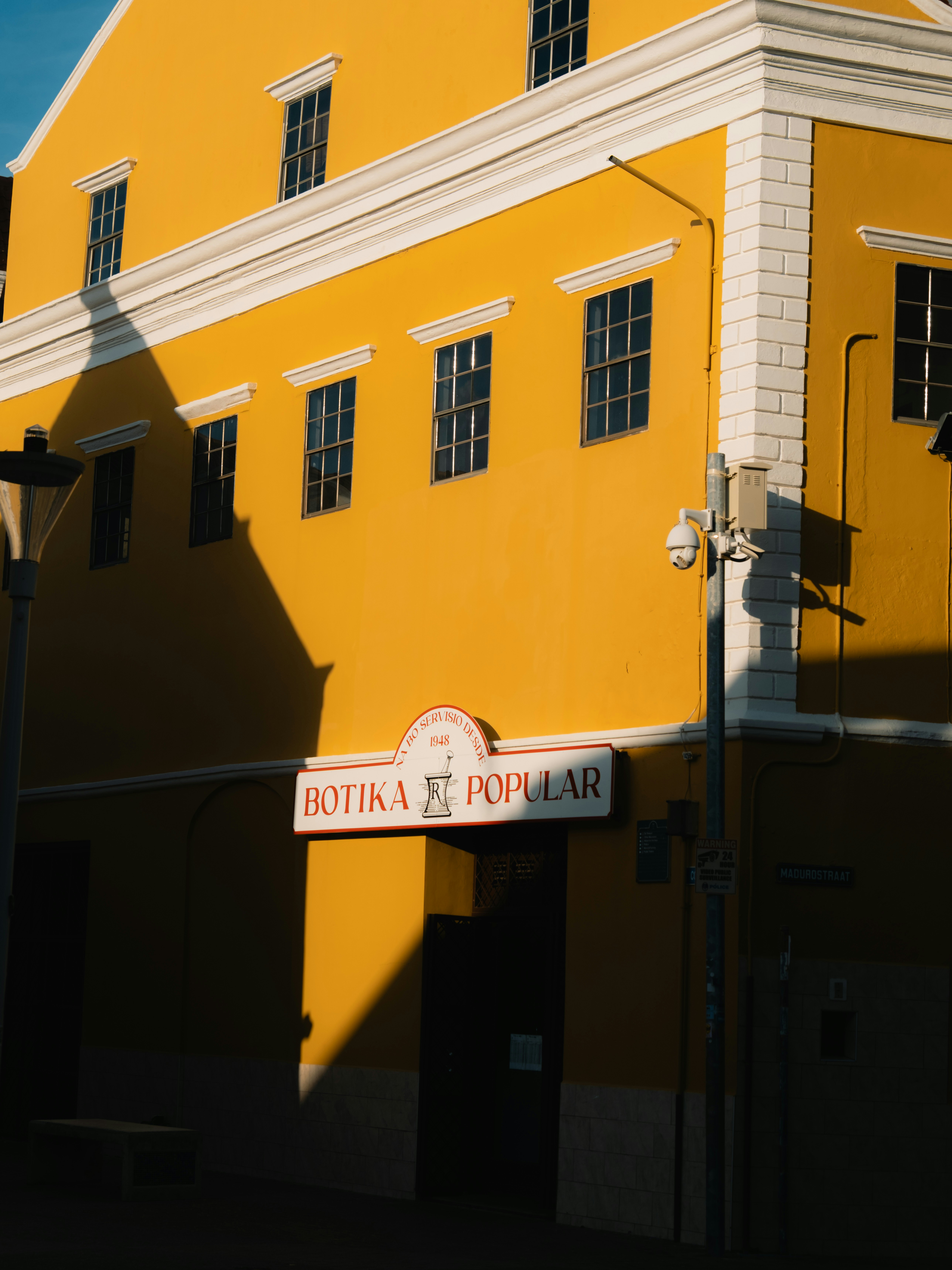 Bright yellow building with a sign that reads botika popular.