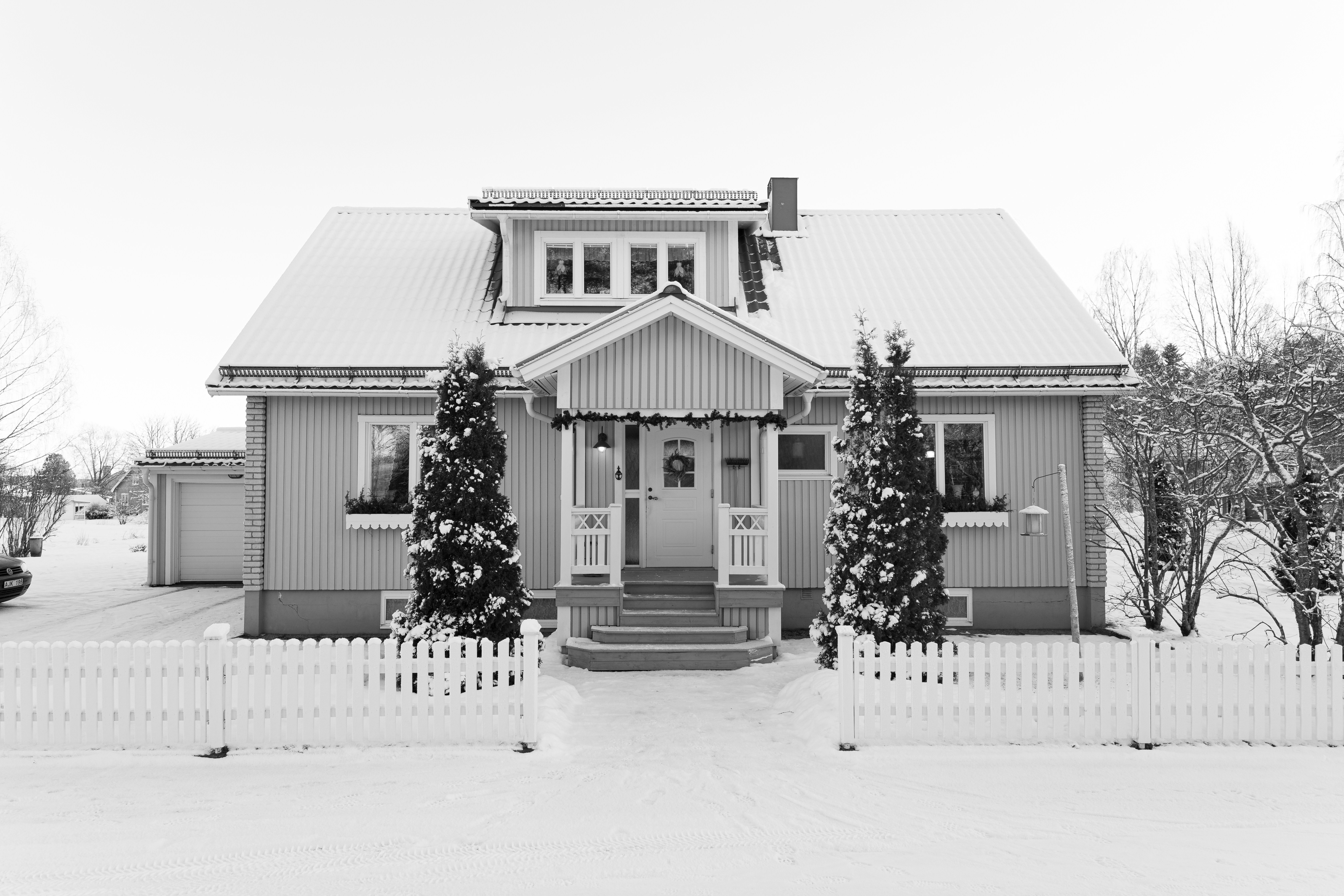 A snow-covered house with a white picket fence.