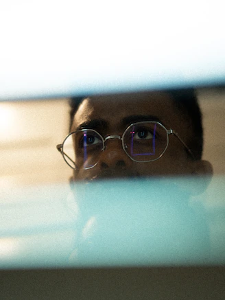 Man with glasses looking intently at a screen.