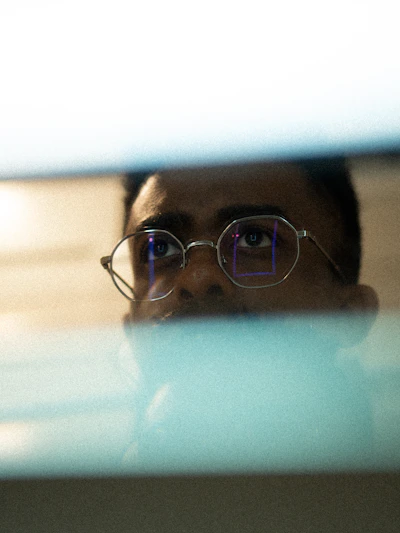 Man with glasses looking intently at a screen.