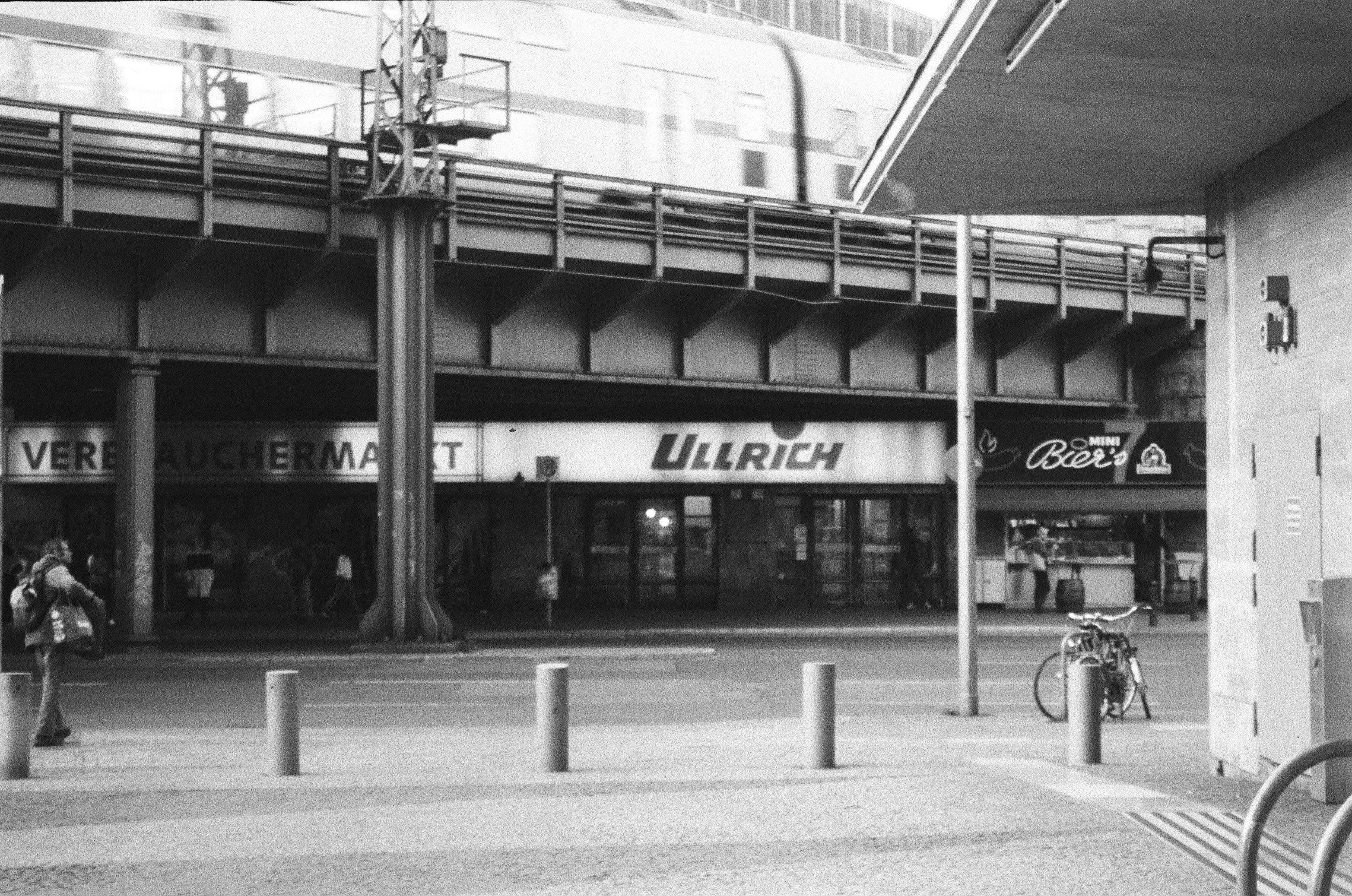 Train passes over a street with shops below.