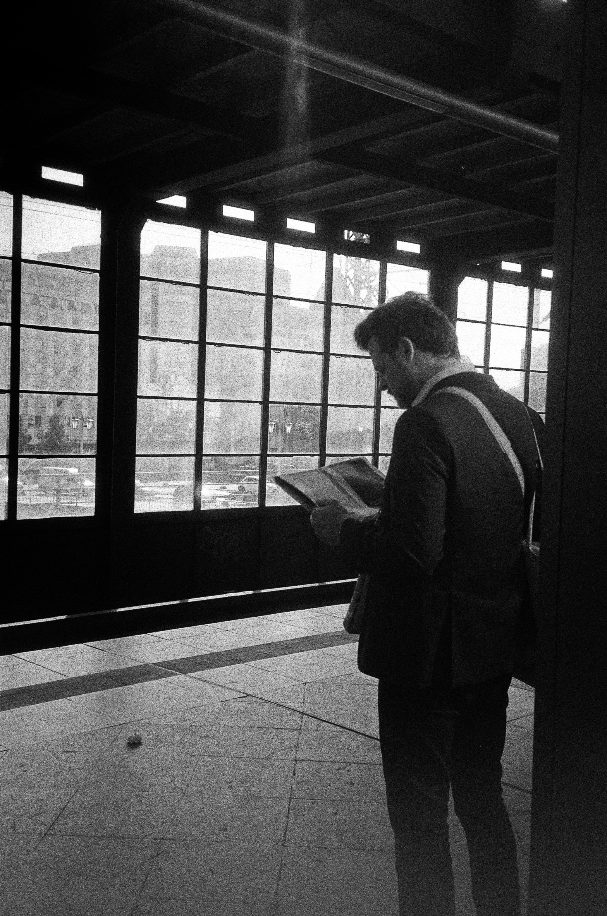 Man reading a book at a train station