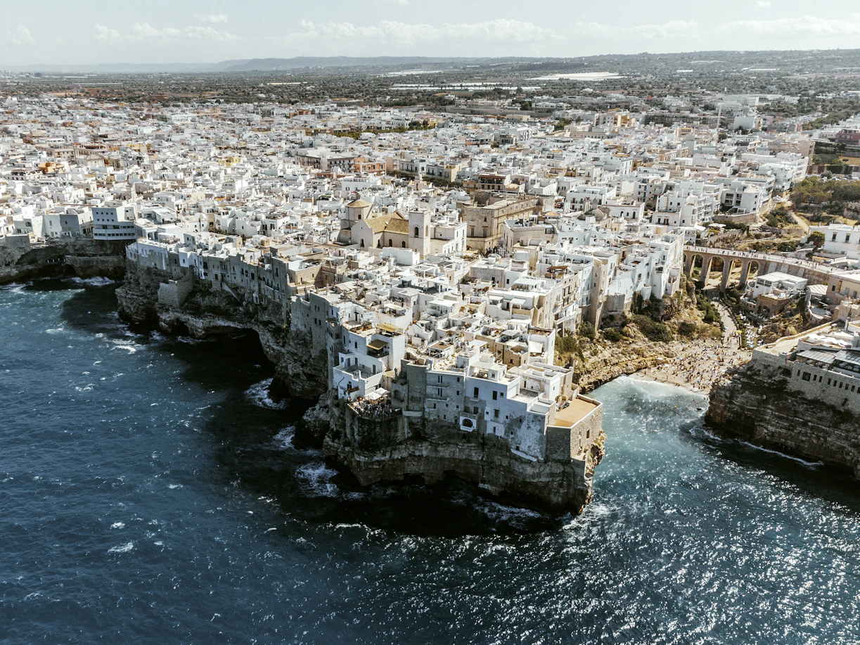 White buildings perched on a rocky coastline overlooking the sea.