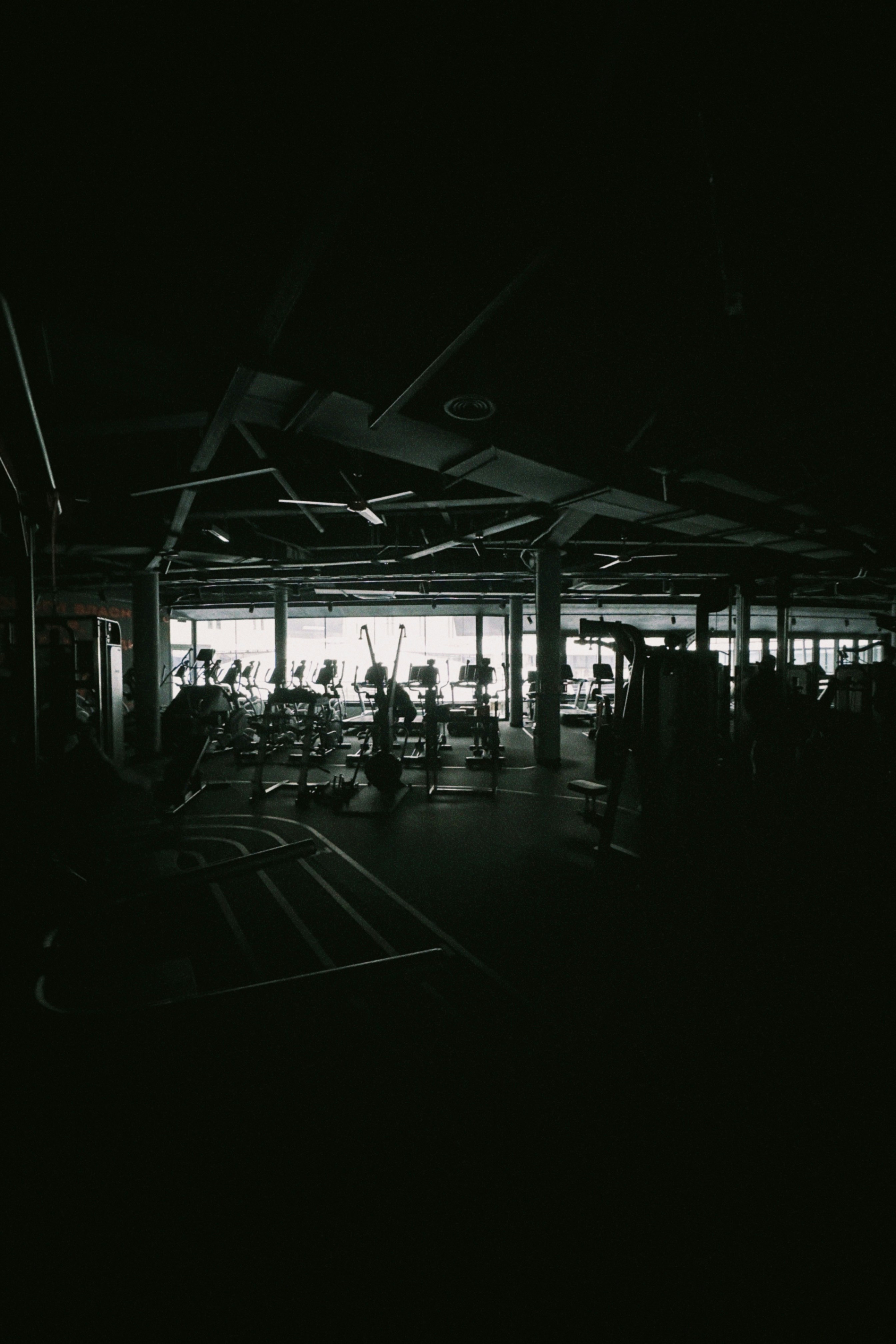 Dark gym interior with exercise equipment visible
