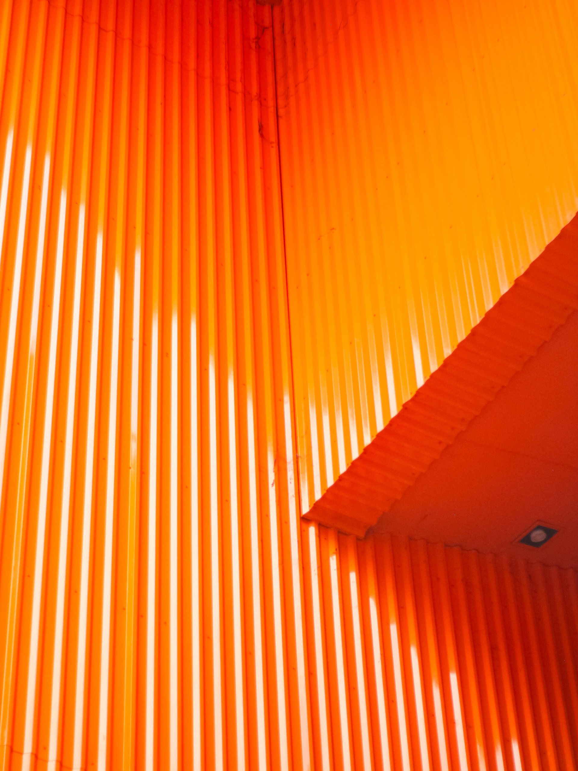 Orange corrugated metal wall with diagonal shadow lines of light