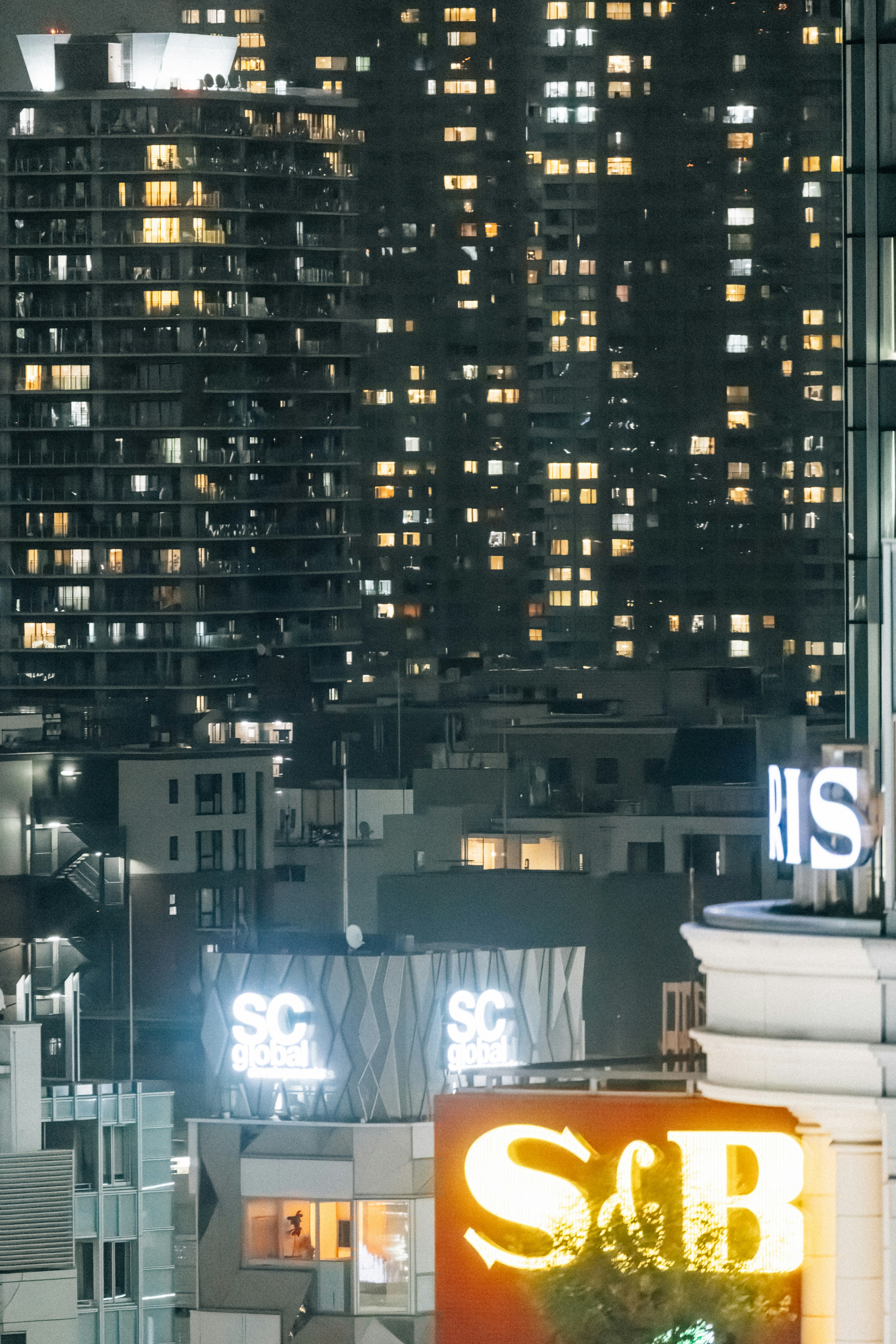 Illuminated buildings in a dense cityscape at night.