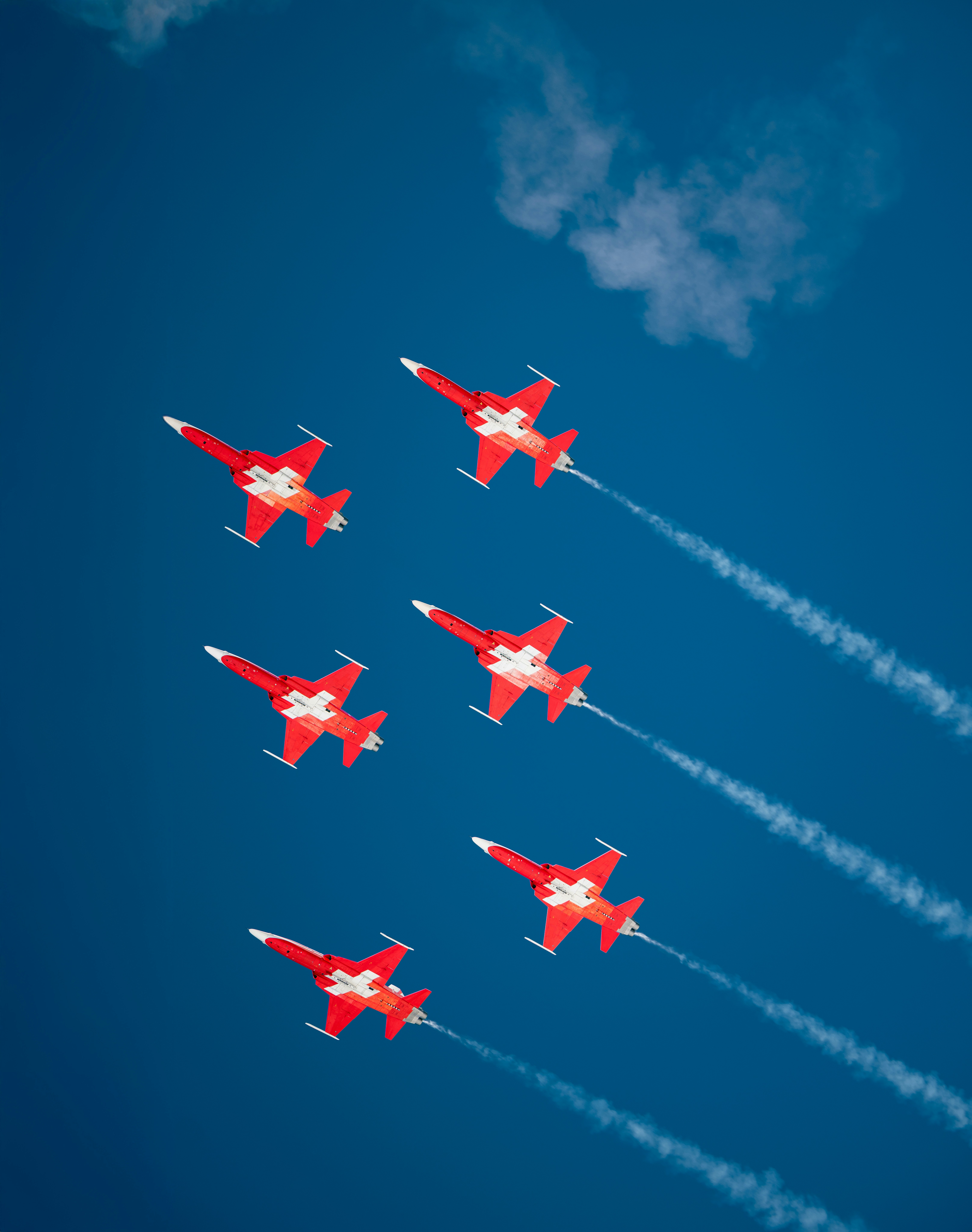 Six red fighter jets flying in formation with smoke trails.
