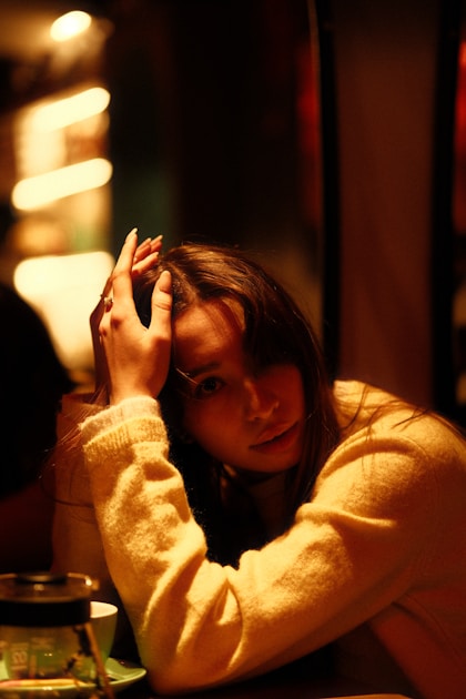Person with hands at their temples in dim light, expressing tension headache or cervicogenic head pain.