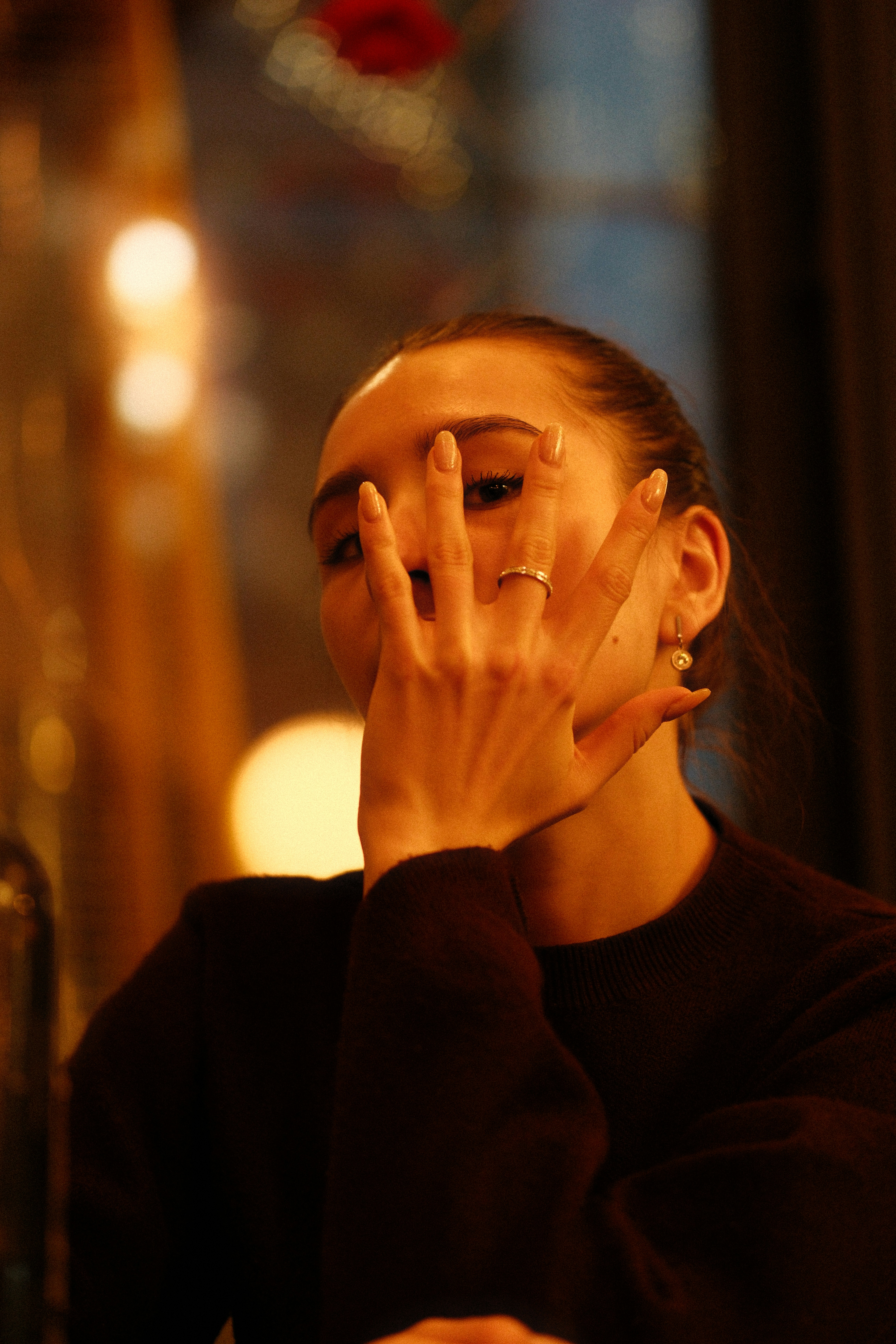 Woman covers face with hand, wearing a ring.