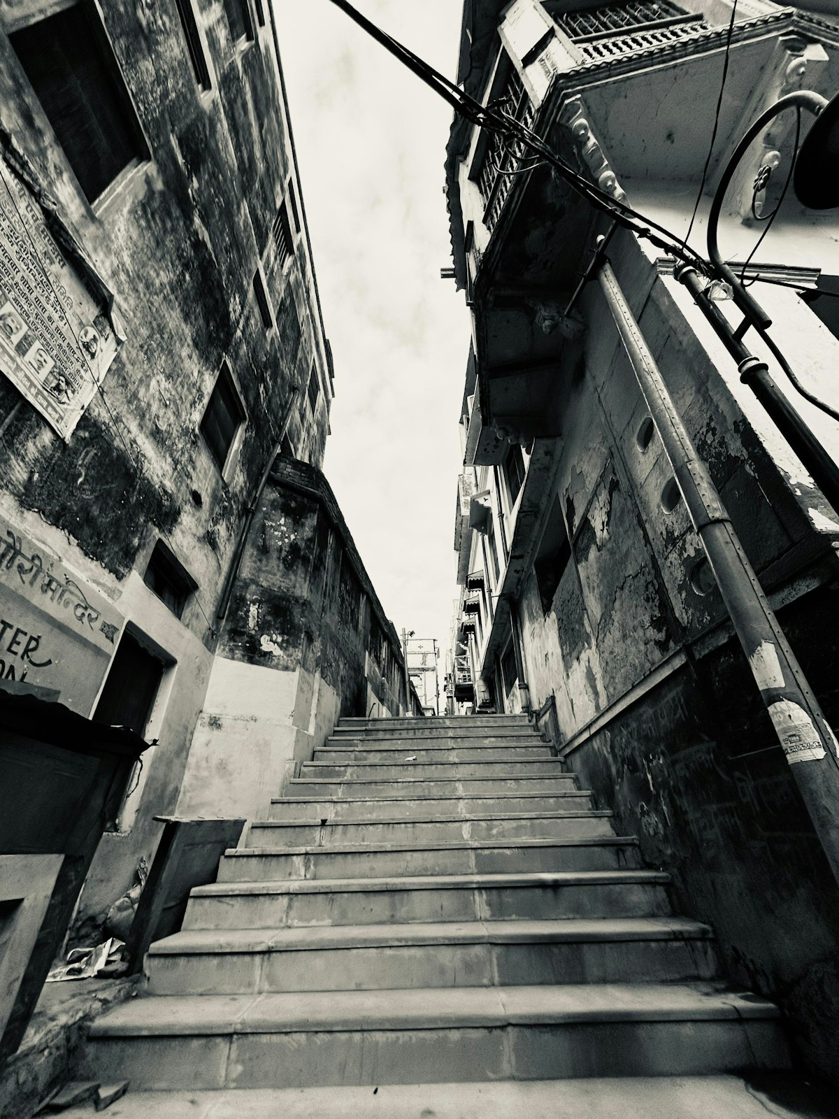 A narrow stone alleyway with steps winding between old buildings in Varanasi's old city
