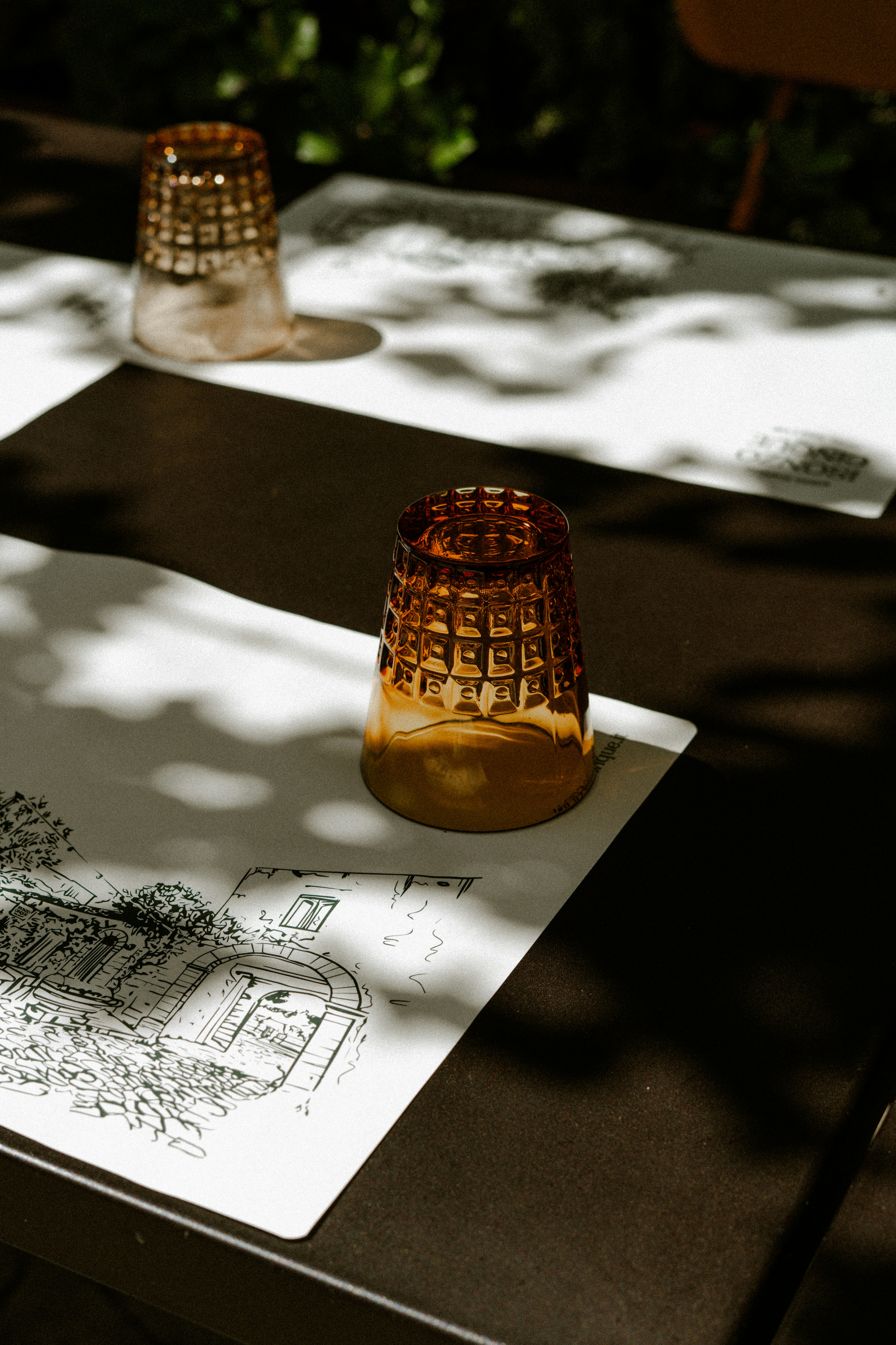 Two amber glasses on placemats with drawings