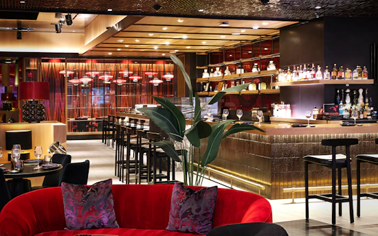 Luxurious bar interior with red velvet seating and bar stools.