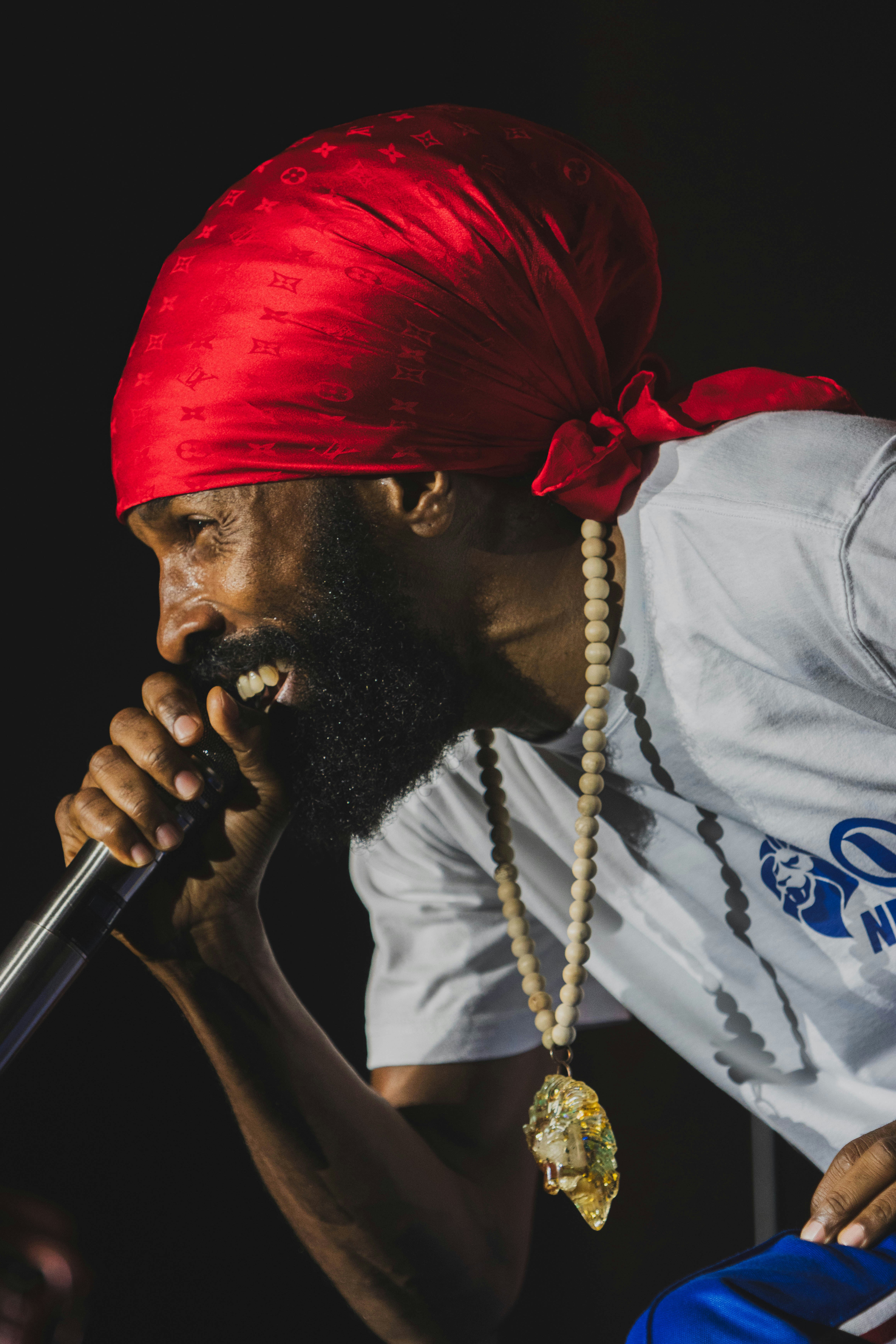 Man wearing a red bandana and necklace singing