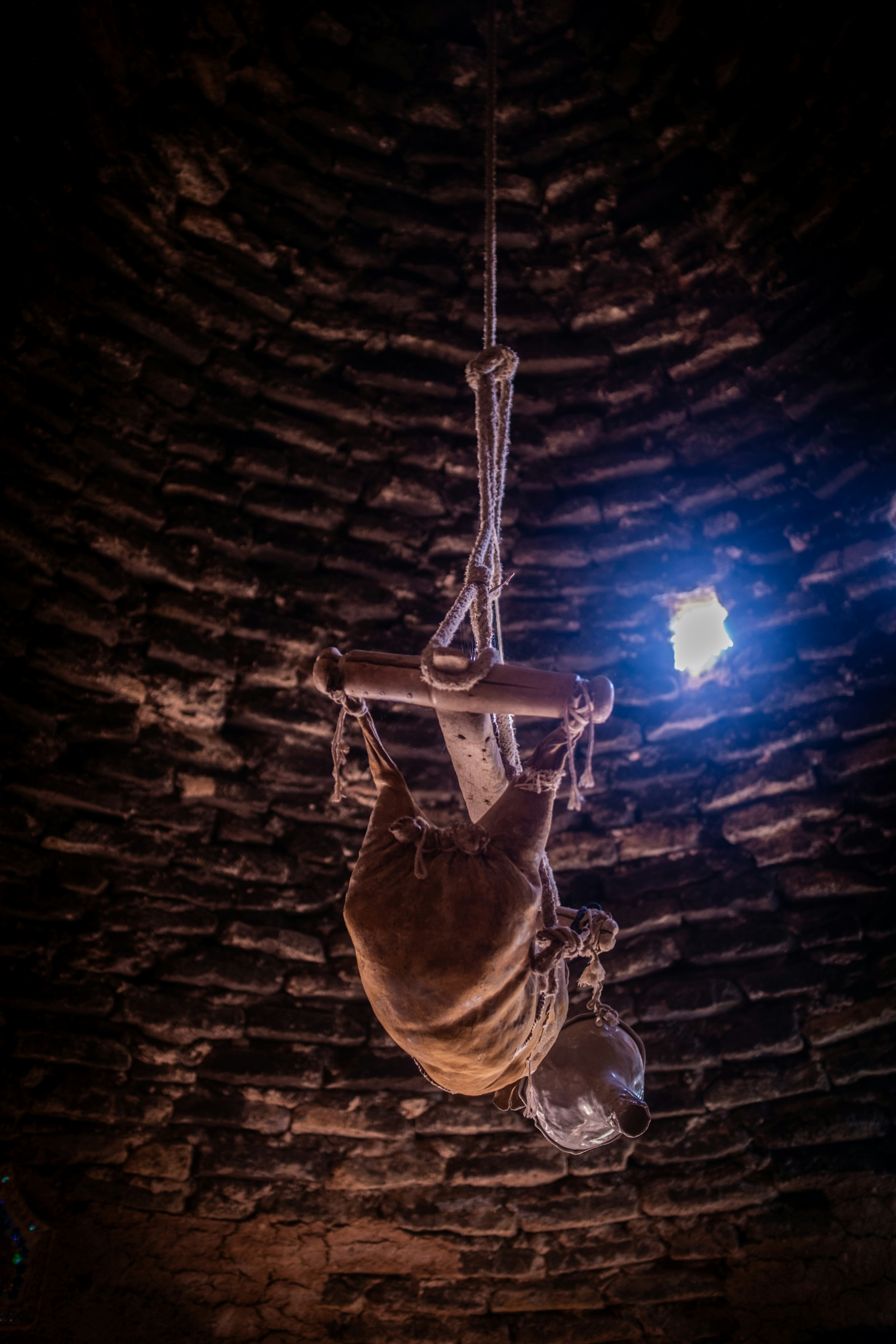 A burlap sack and jug hang from a rope.