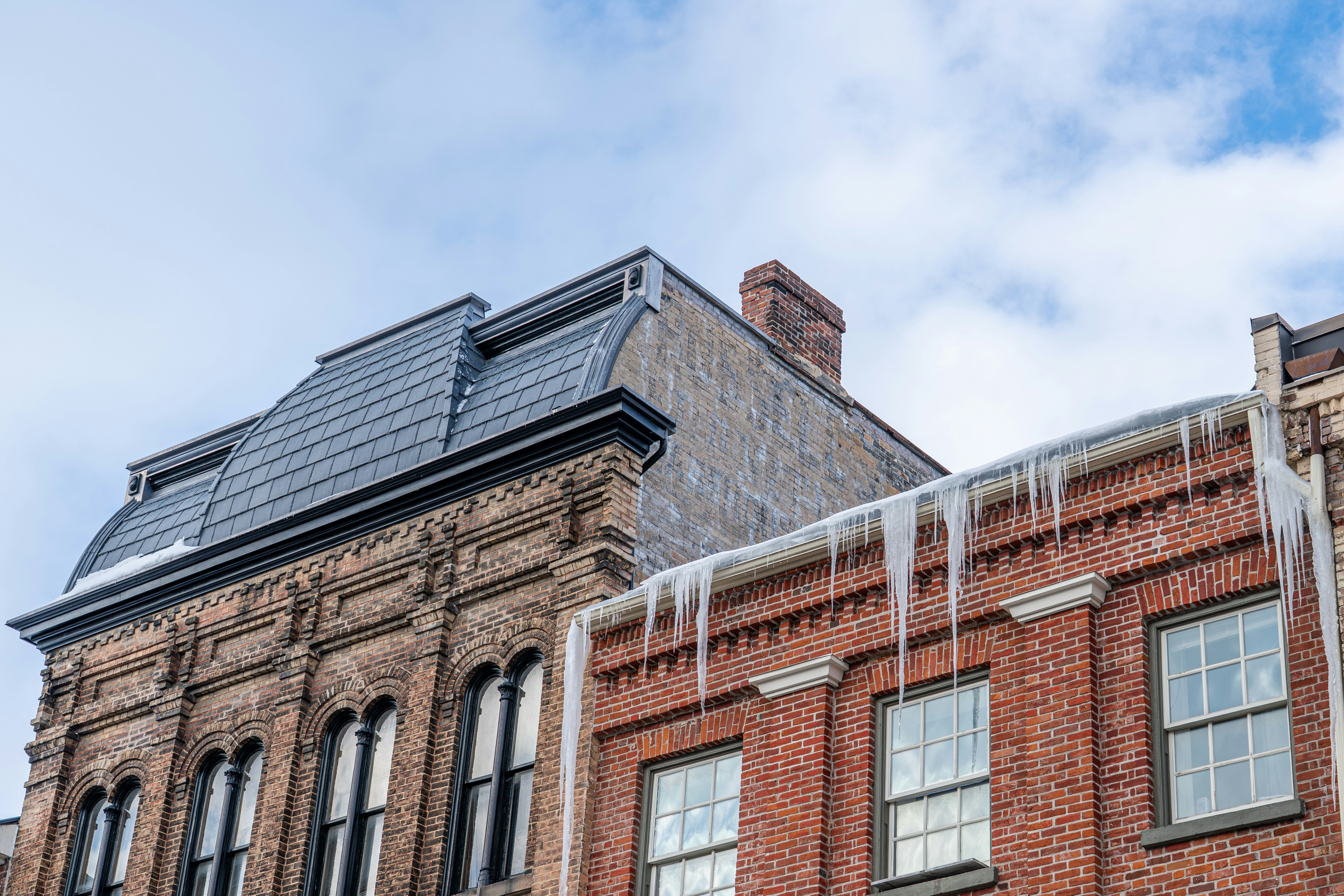 Des glaçons pendent sur les toits des bâtiments en briques.