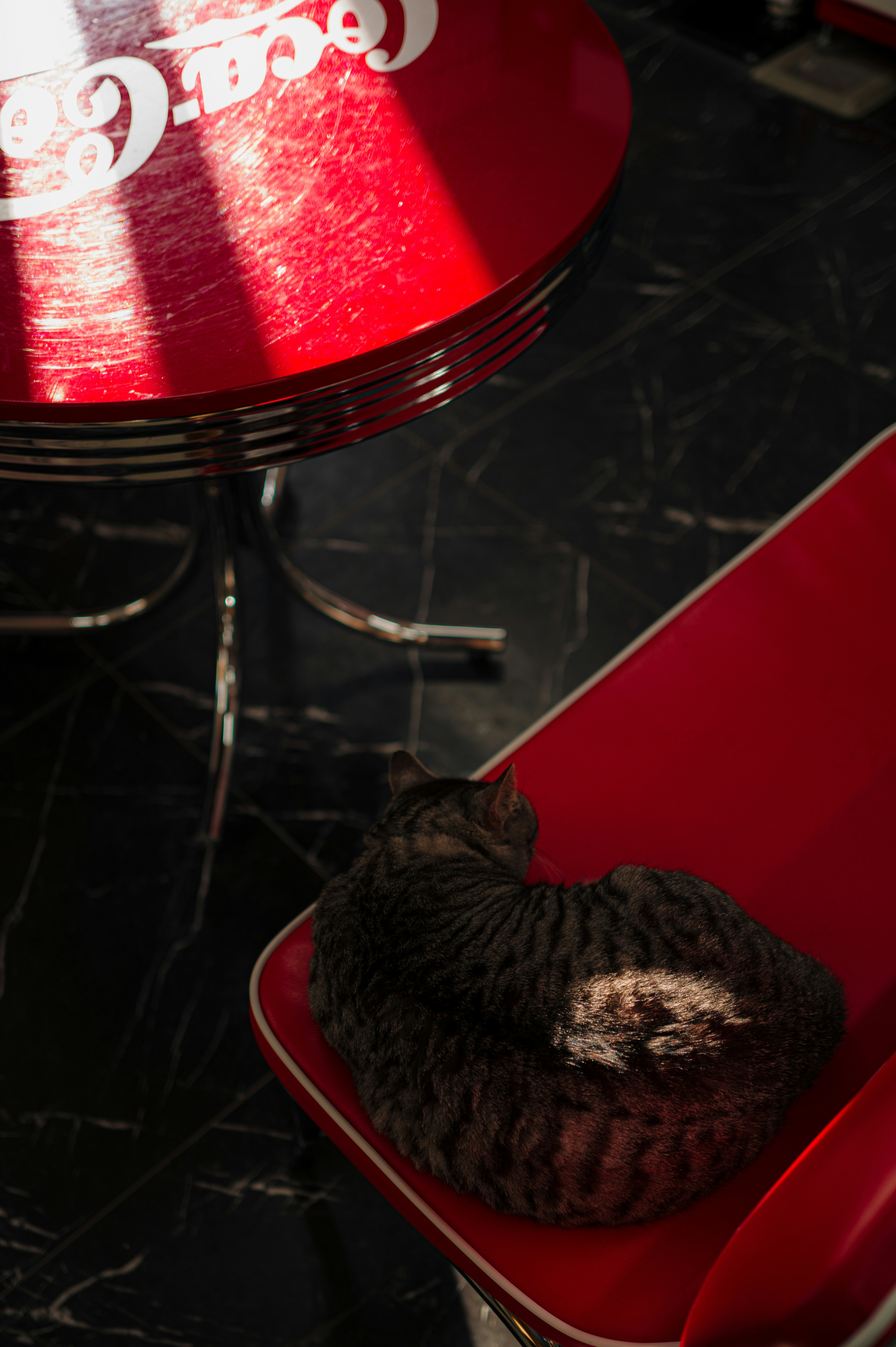 A tabby cat sleeps on a red chair.