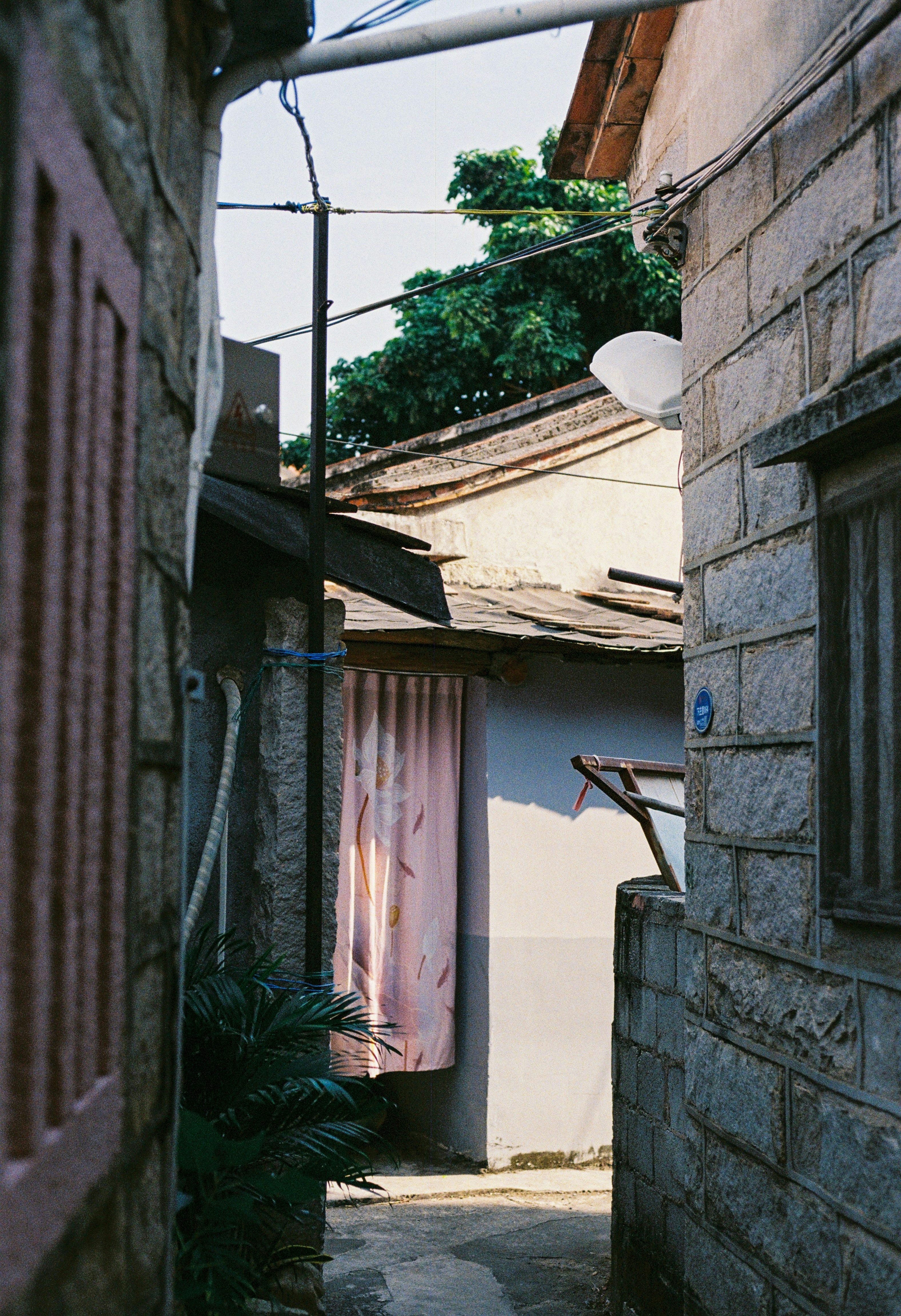 Narrow alleyway between stone buildings with pink curtain.