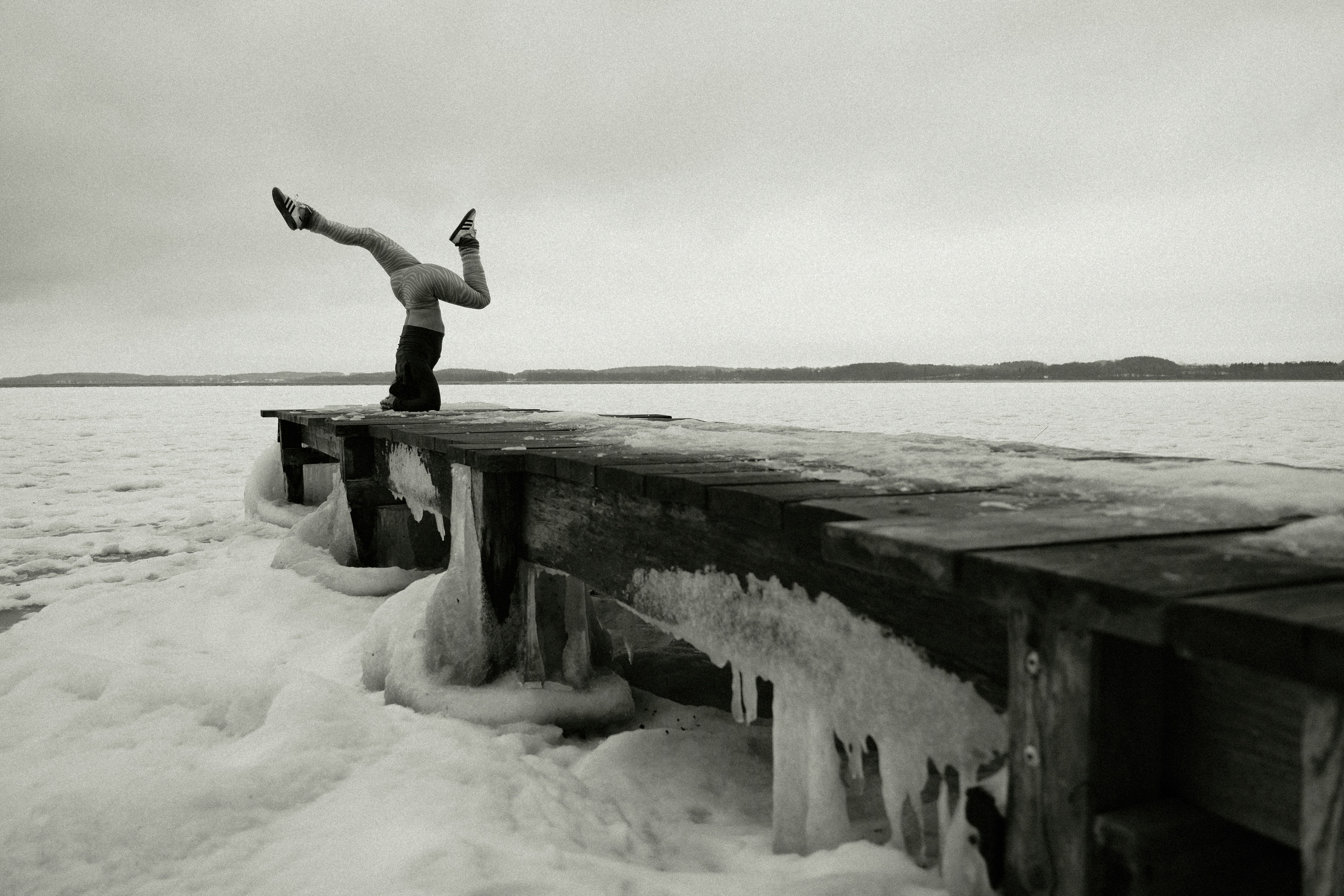Persona che fa una verticale su un molo ghiacciato