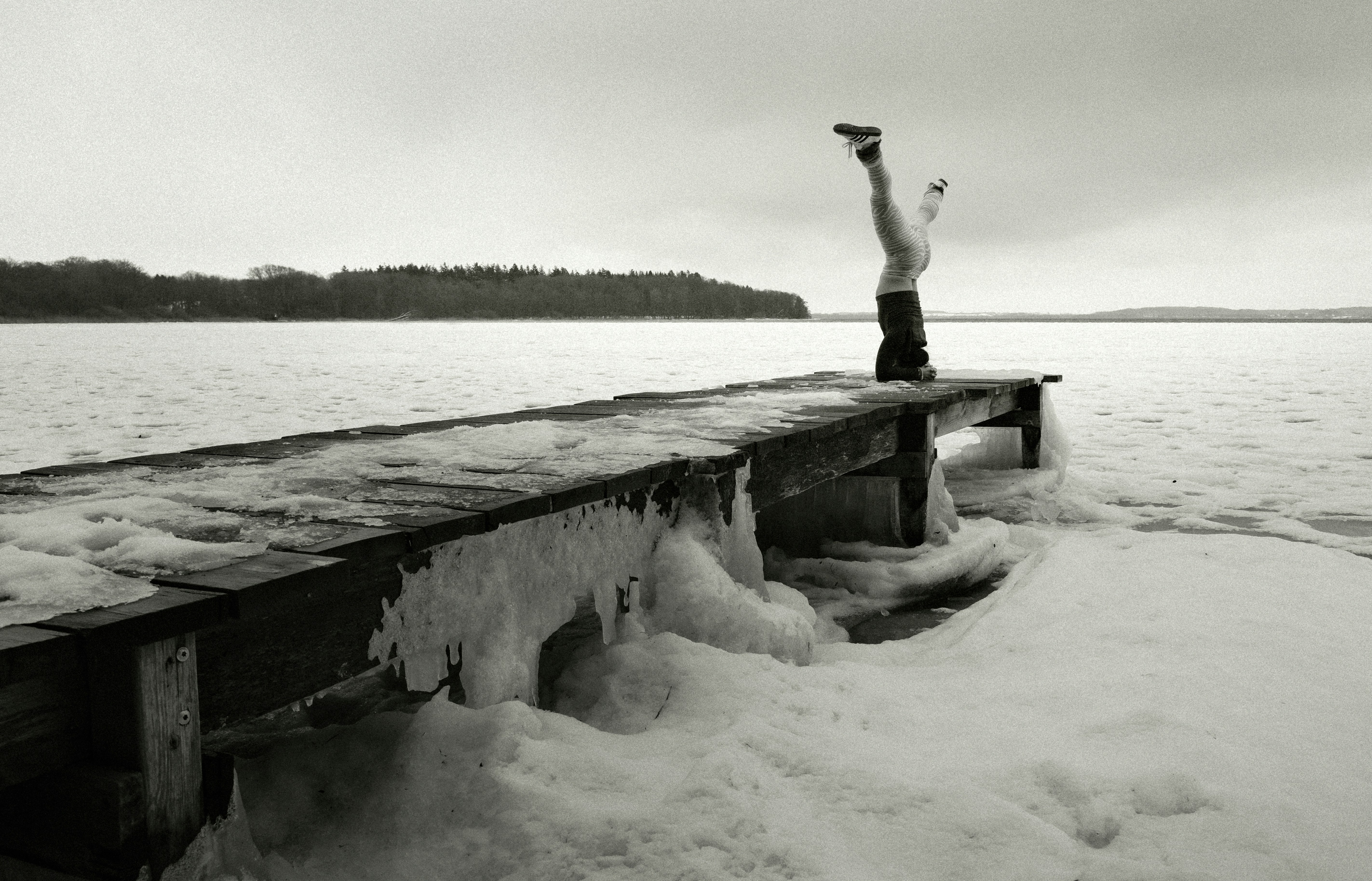Persona che fa una verticale su un molo ghiacciato