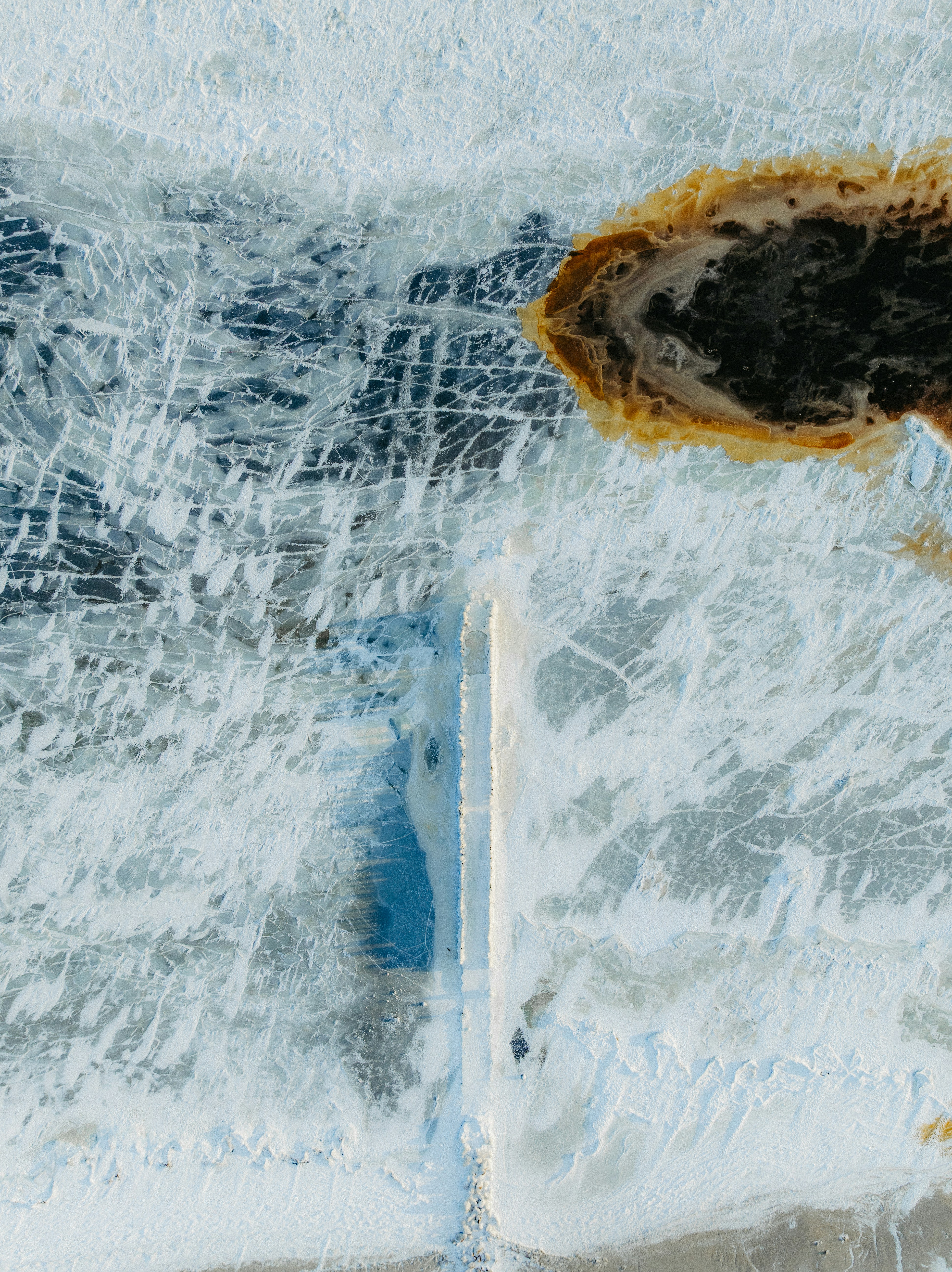 Abstract aerial view of cracked ice and dark water
