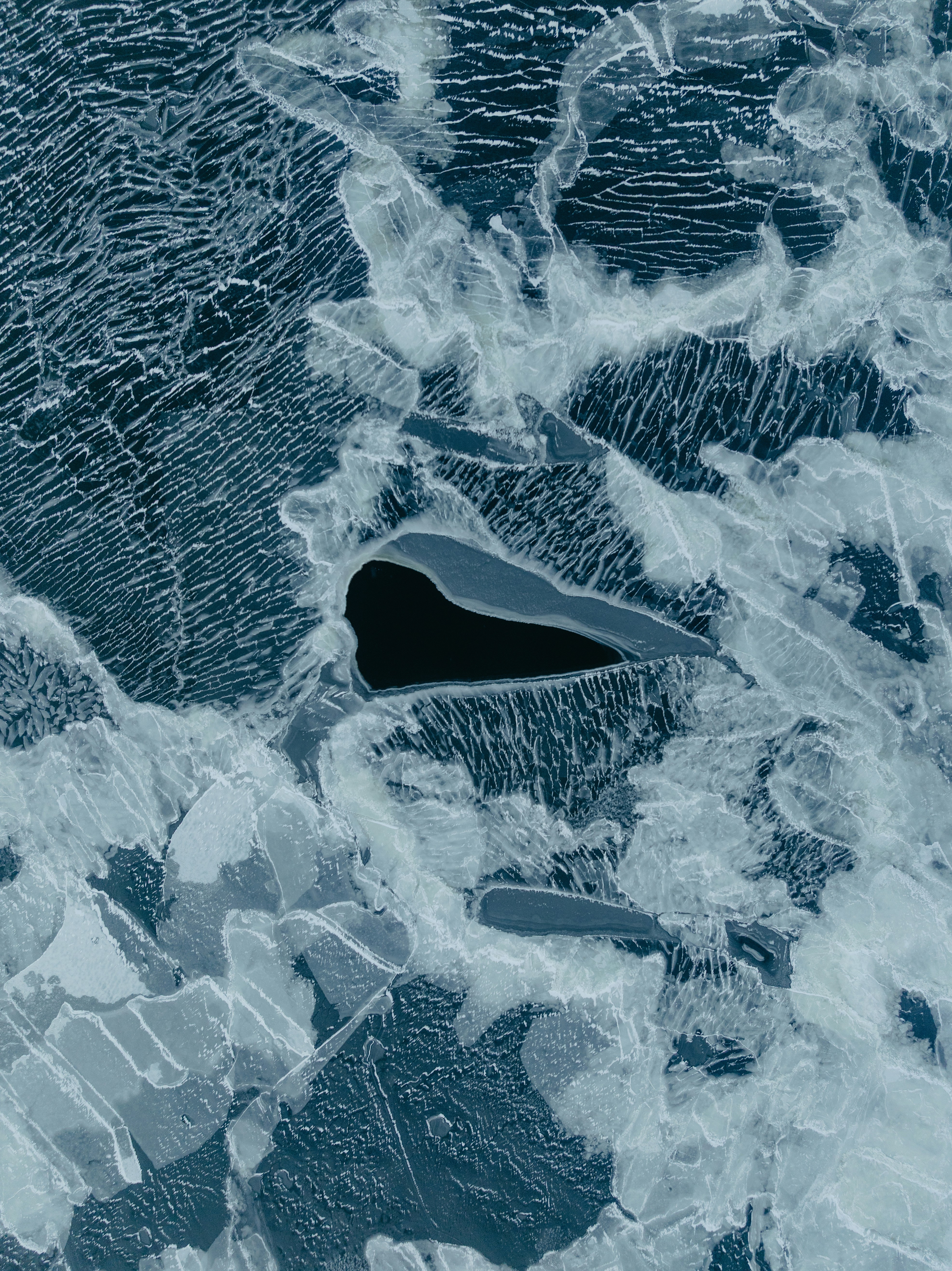 Abstract pattern of ice with dark water pockets.