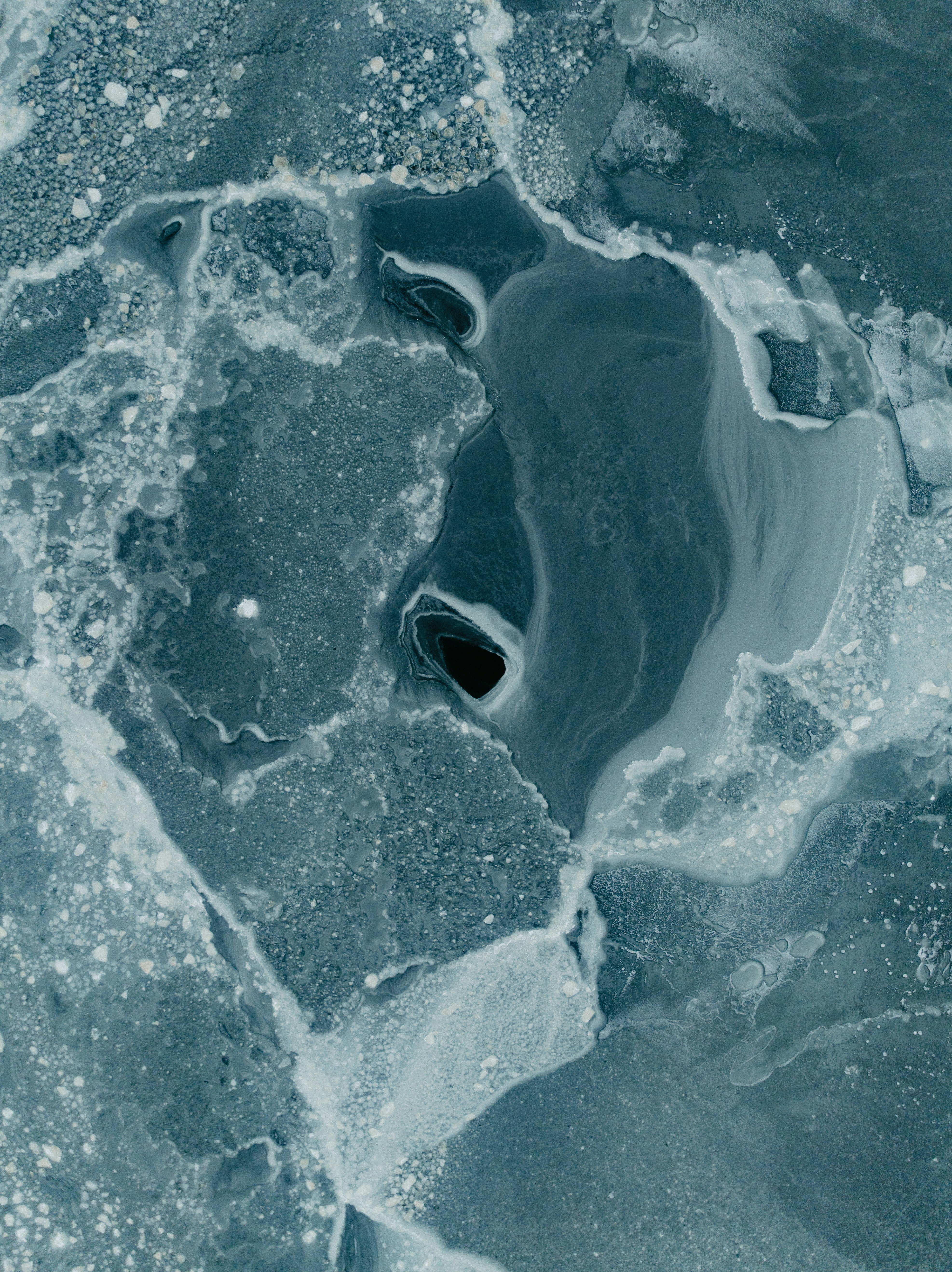 Abstract pattern of ice and water with dark hole.