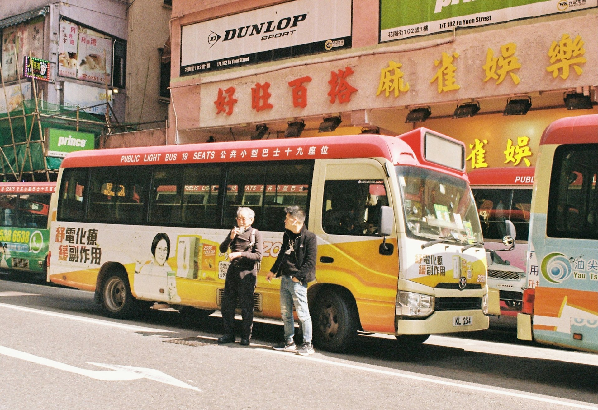 Two people stand by a colorful bus on a street.