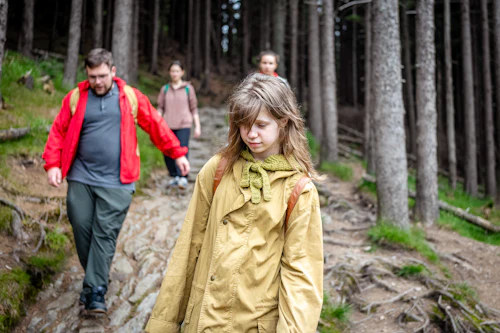 Famille en vestes de pluie sur un sentier entre les sapins