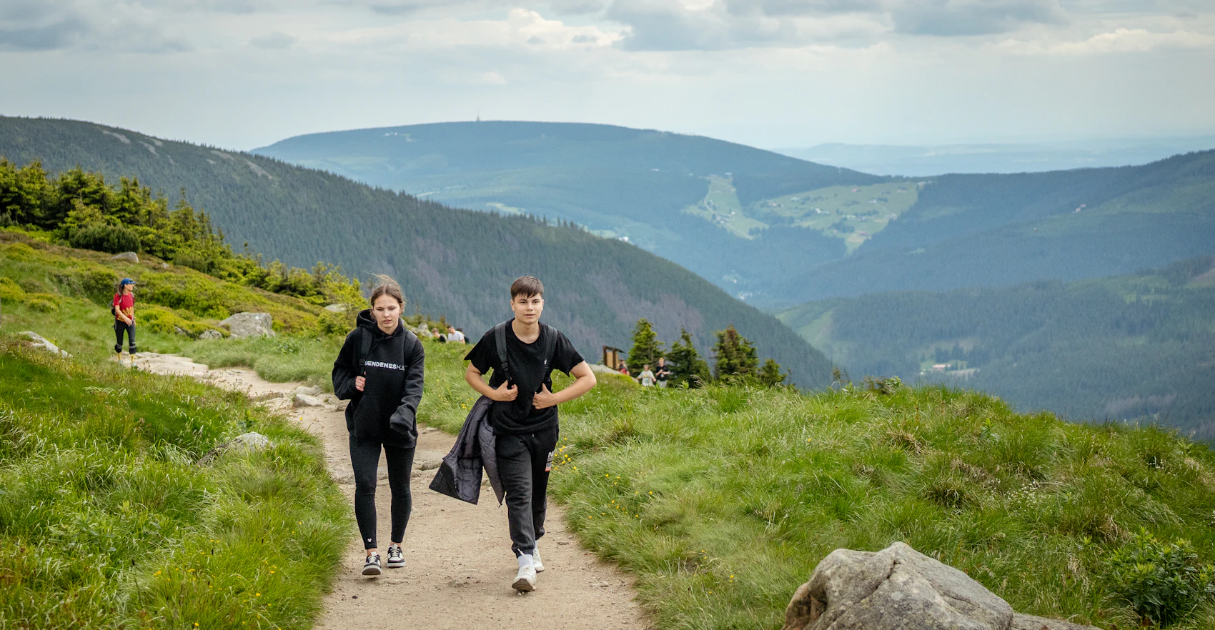 Two travellers hiking together along a mountain trail