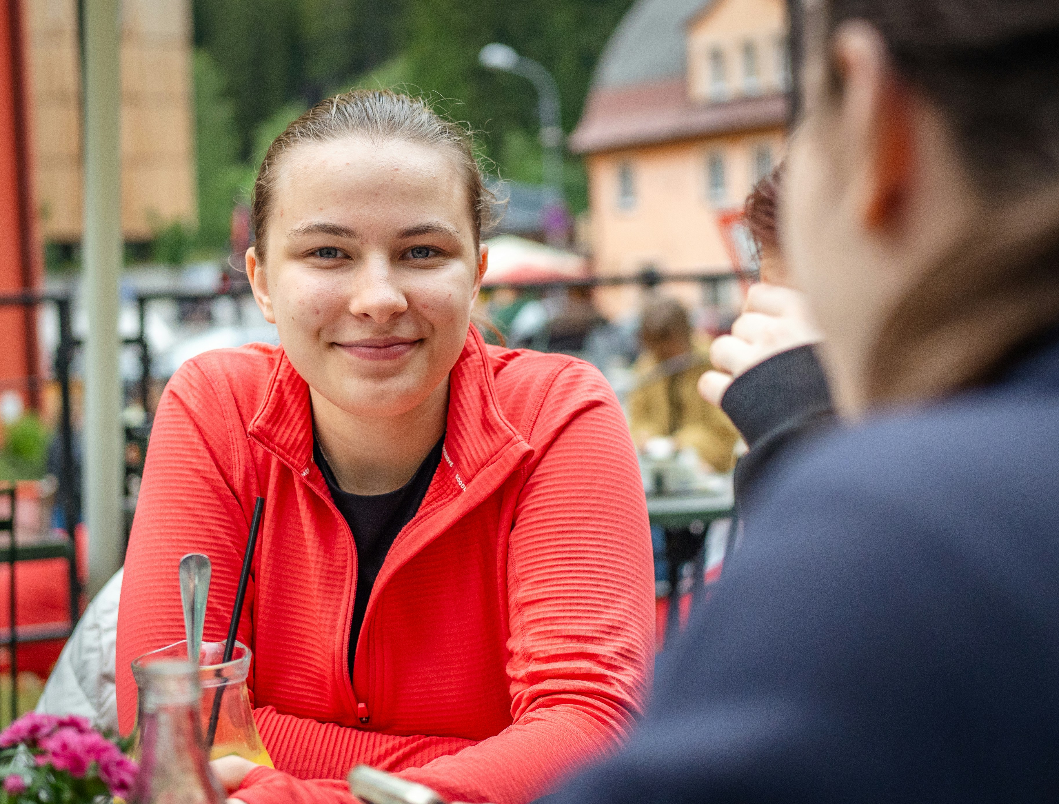 Young woman in red jacket smiling at cafe
