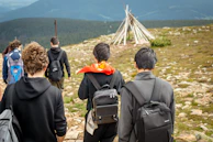 Hikers walk up a rocky mountain path towards a teepee