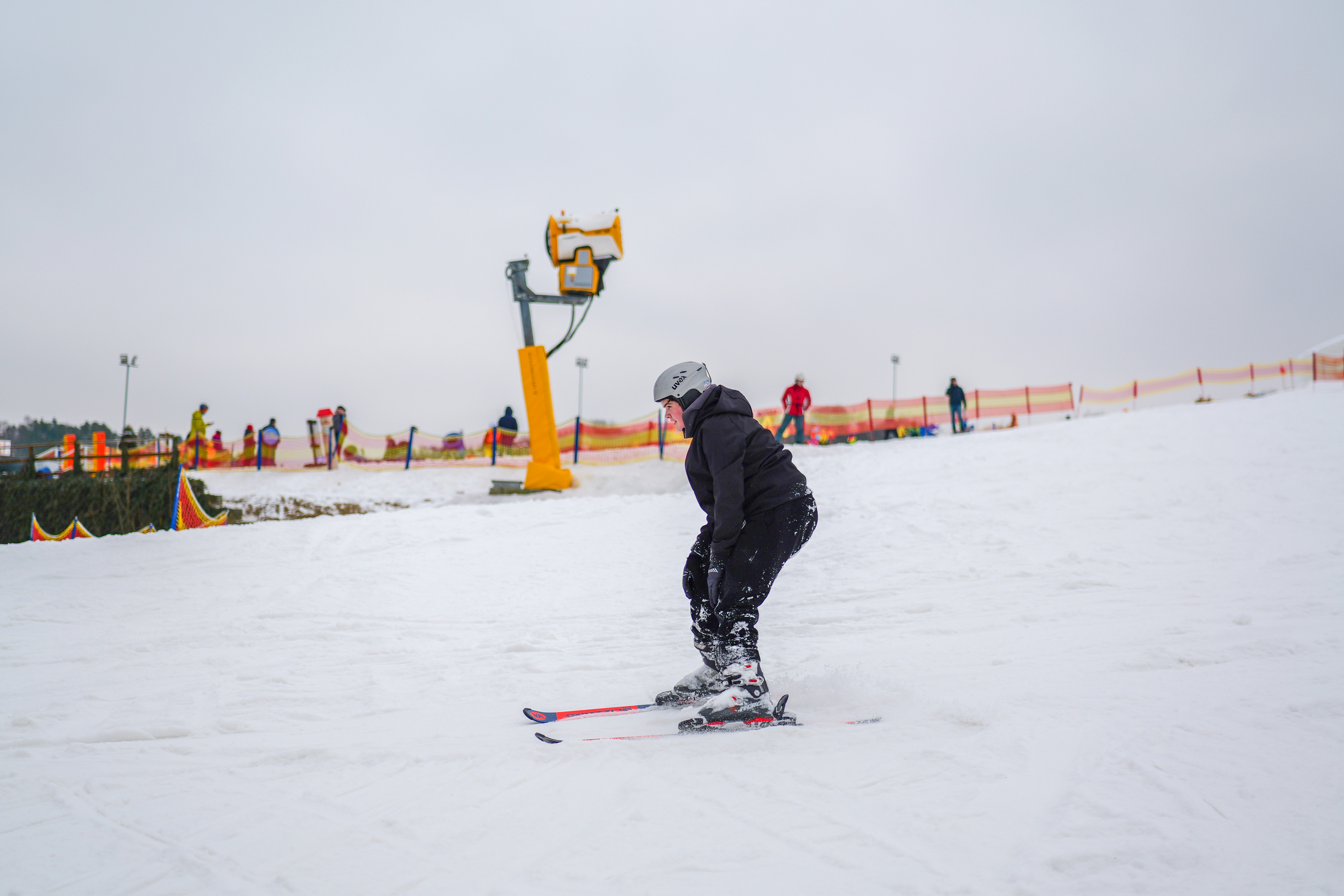 A person skiing down a snowy slope with ski lift.