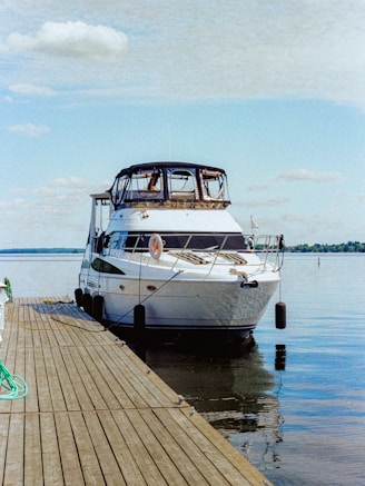 A white yacht docked at a wooden pier.