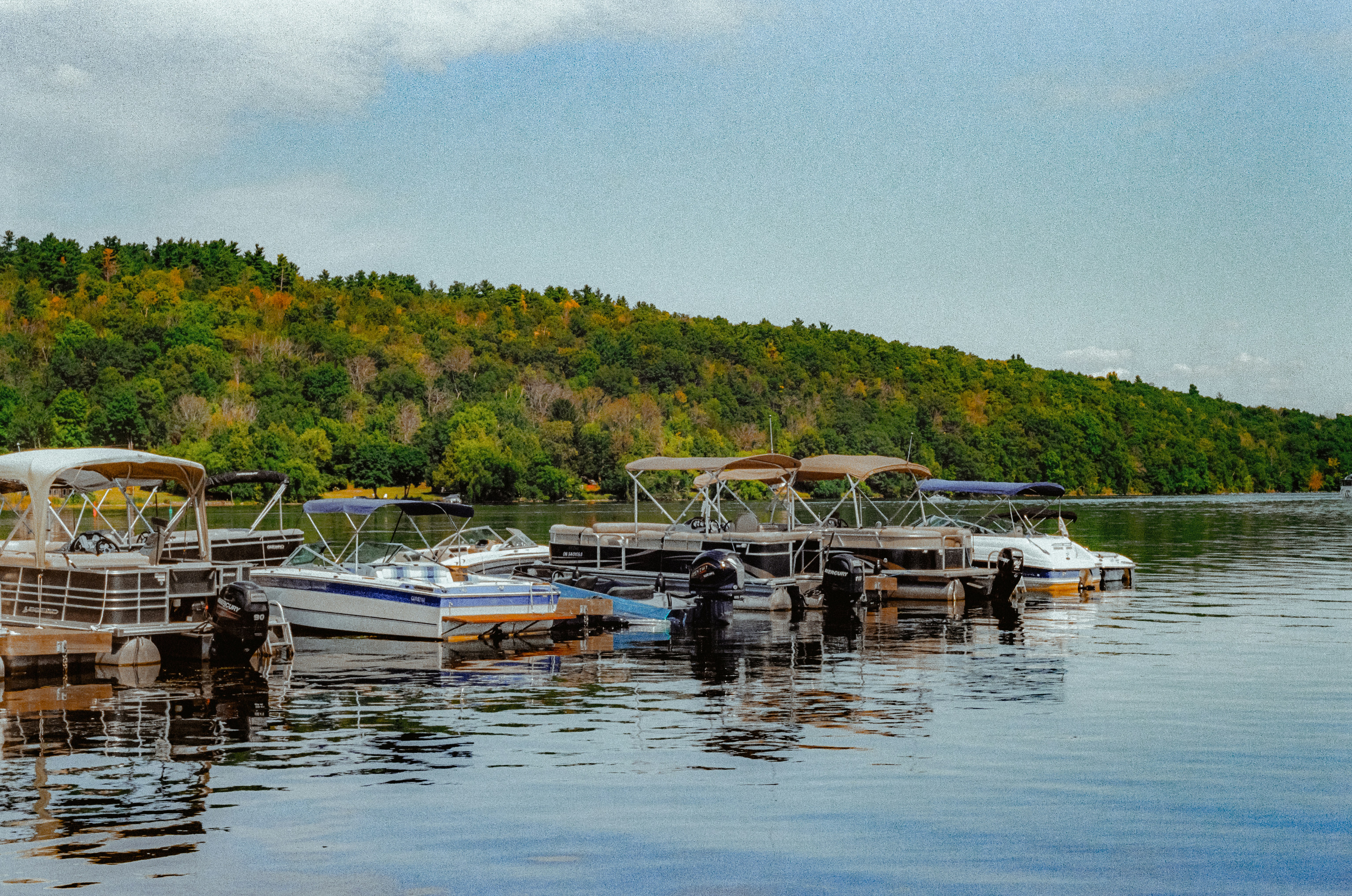 Mehrere Boote legten an einem ruhigen See mit bewaldeten Hügeln an.